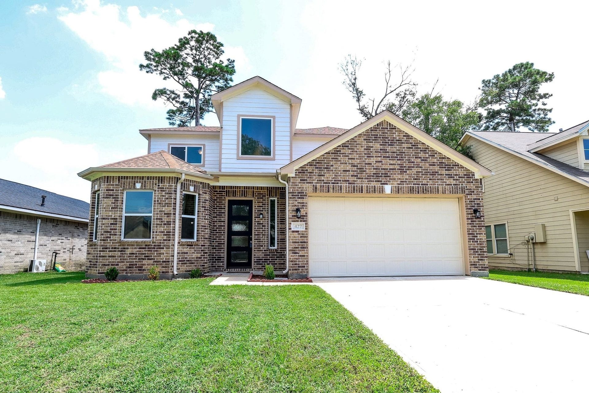 Charming brick home with modern design, featuring a spacious two-car garage and a well-maintained lawn, perfect for family living.