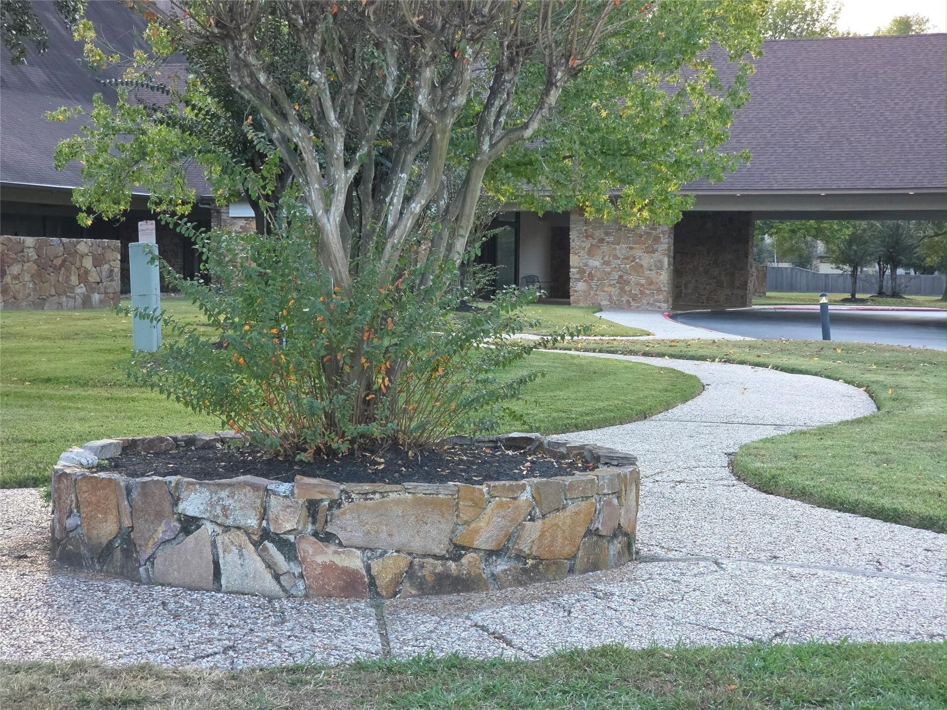 Charming stone-lined landscaping complements a winding walkway leading to the inviting entrance to the community clubhouse..