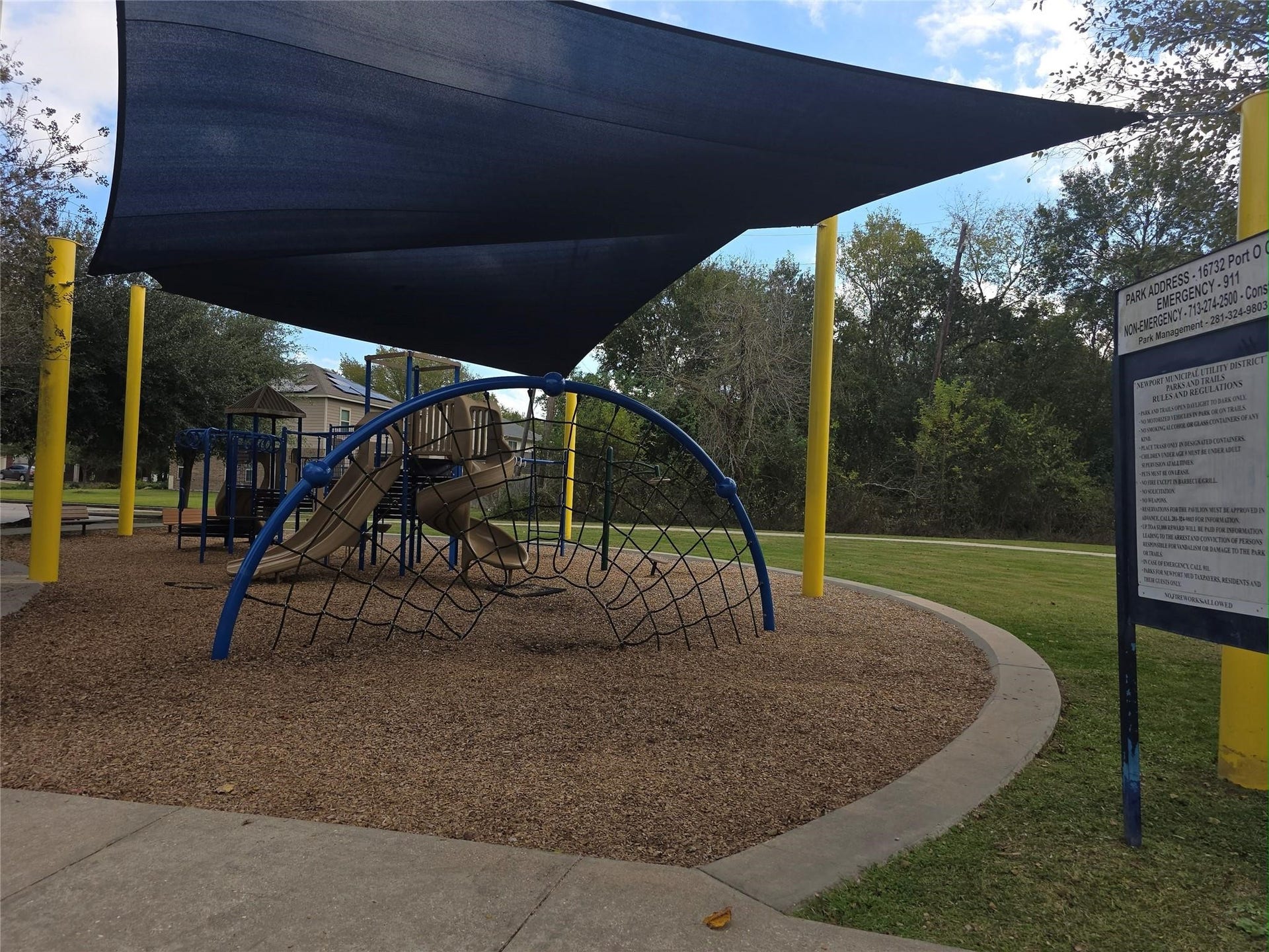 A charming playground with shaded structures, climbing equipment, and slides, set in a lush, green park perfect for family fun and outdoor activities.