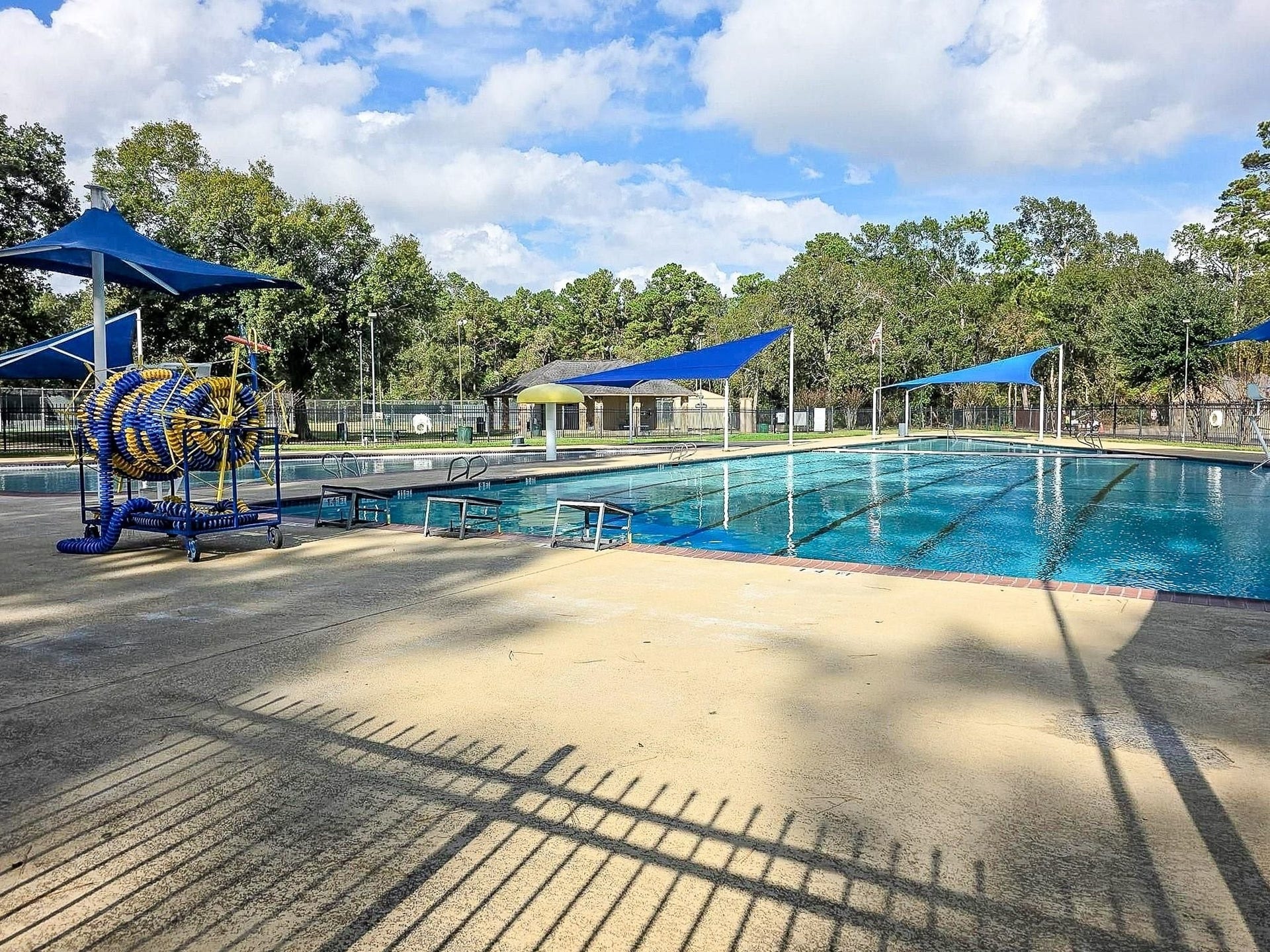 Dive into a spacious outdoor pool area with shaded seating, ideal for relaxation and leisure.