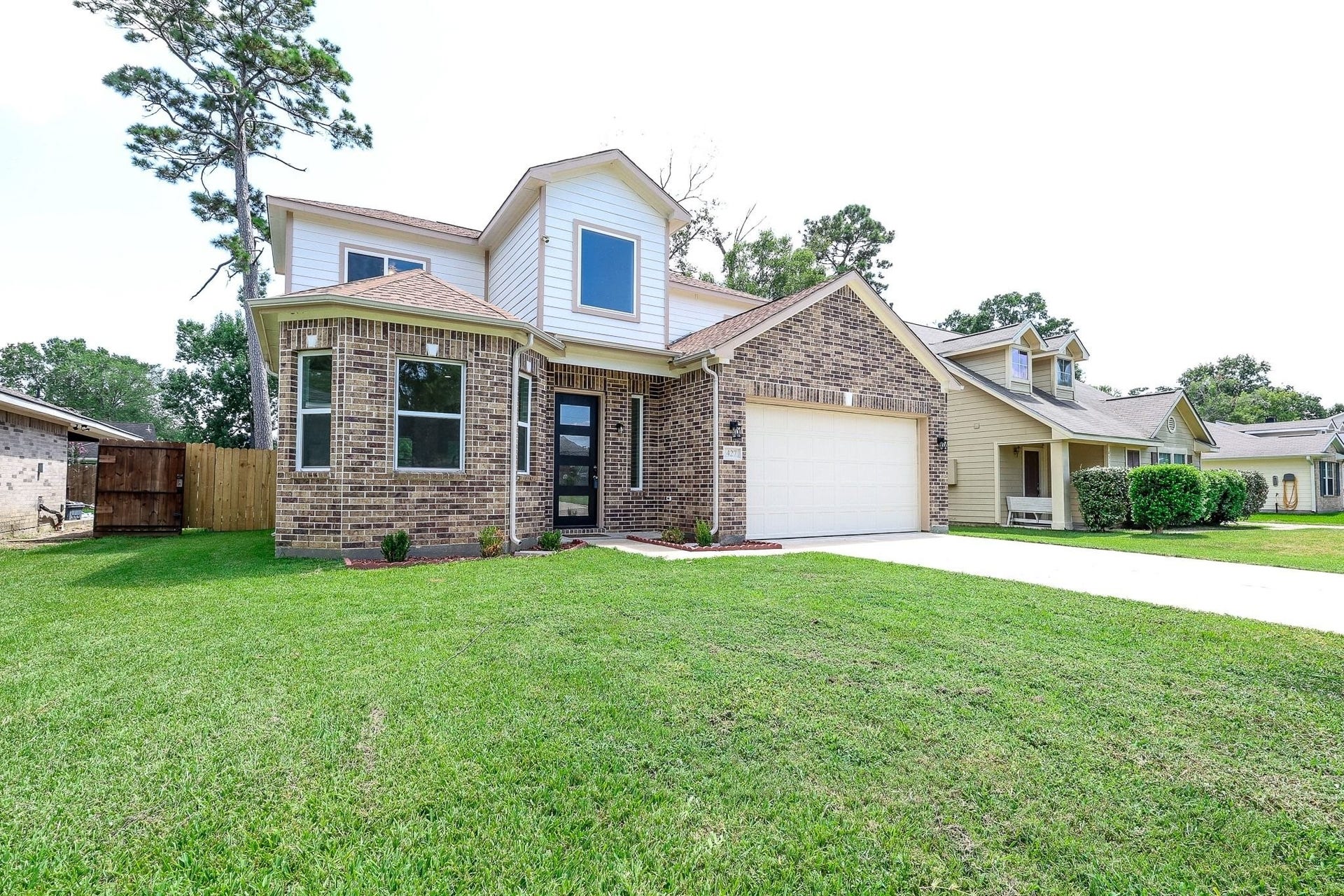 Charming two-story brick home with a modern facade, featuring a spacious front yard and an attached garage.