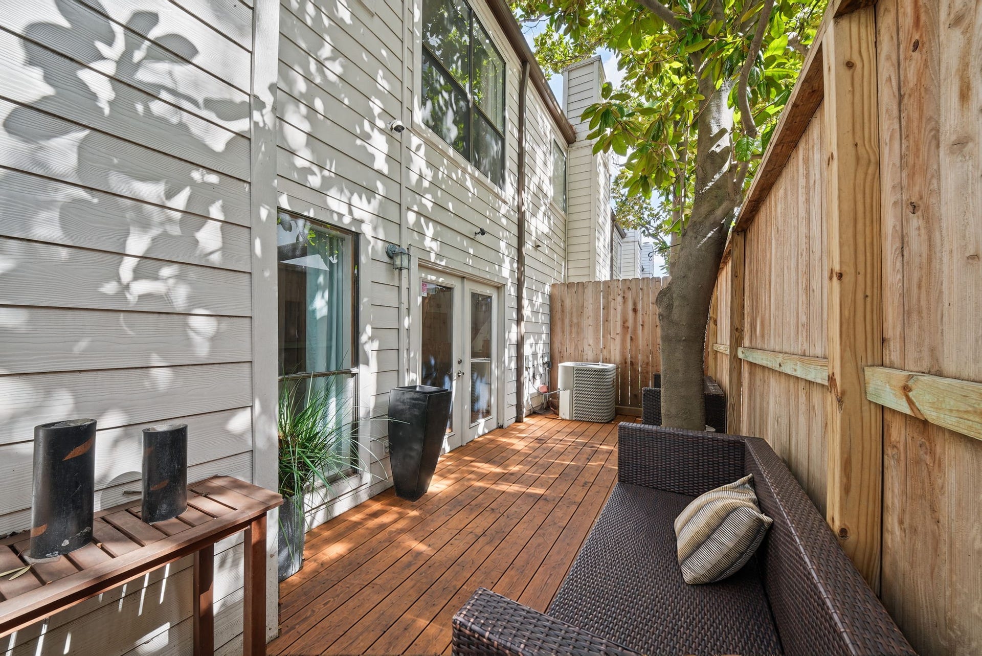 2555 Bering Drive, #1, Houston, TX 77057 Charming private patio with wooden decking, shaded by a tree, offering a cozy outdoor seating area, perfect for evening relaxing or having your morning coffee outside.
