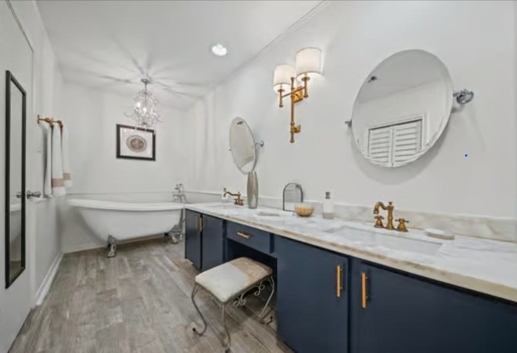 2555 Bering Drive, #1, Houston, TX 77057 Elegant owner's suite bathroom featuring a classic clawfoot tub, dual sinks with marble countertops, and sophisticated gold fixtures, all illuminated by a stylish chandelier.