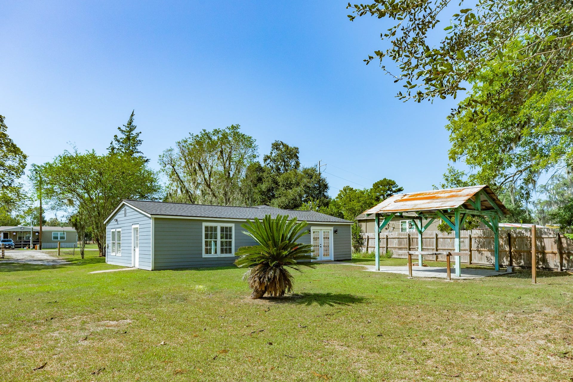 1602 County Road 939, Sweeny, TX 77480 Beautifully open yard features mature landscaping, a decorative palm, and a freestanding covered pavilion with a paved surface. A wonderful setting for outdoor gatherings and enjoying the surrounding greenery.
