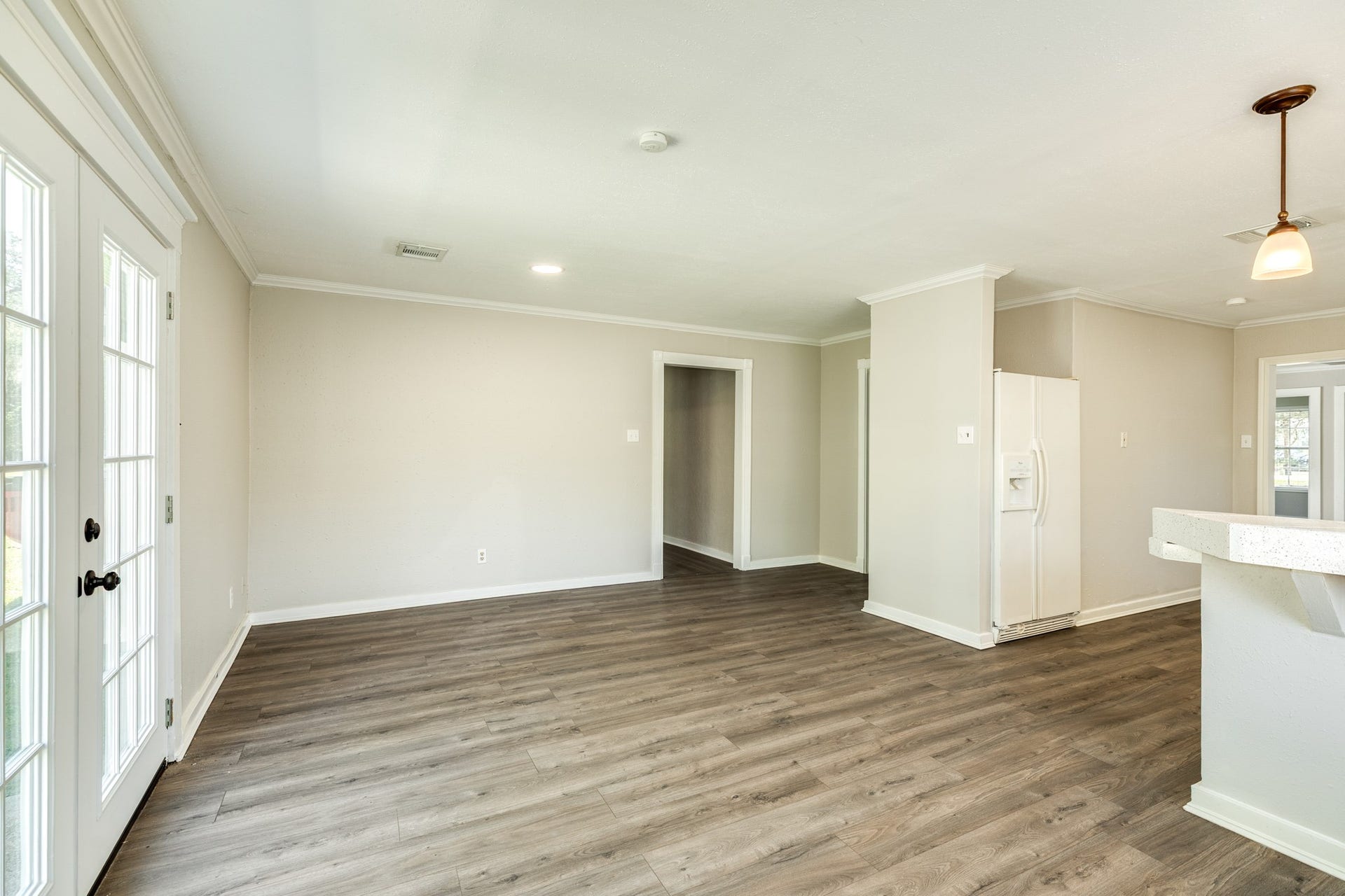 1602 County Road 939, Sweeny, TX 77480 Open and versatile living and dining space showcases attractive wood-look flooring, neutral wall colors, and crown molding. French doors provide natural light and convenient access to the outdoors.