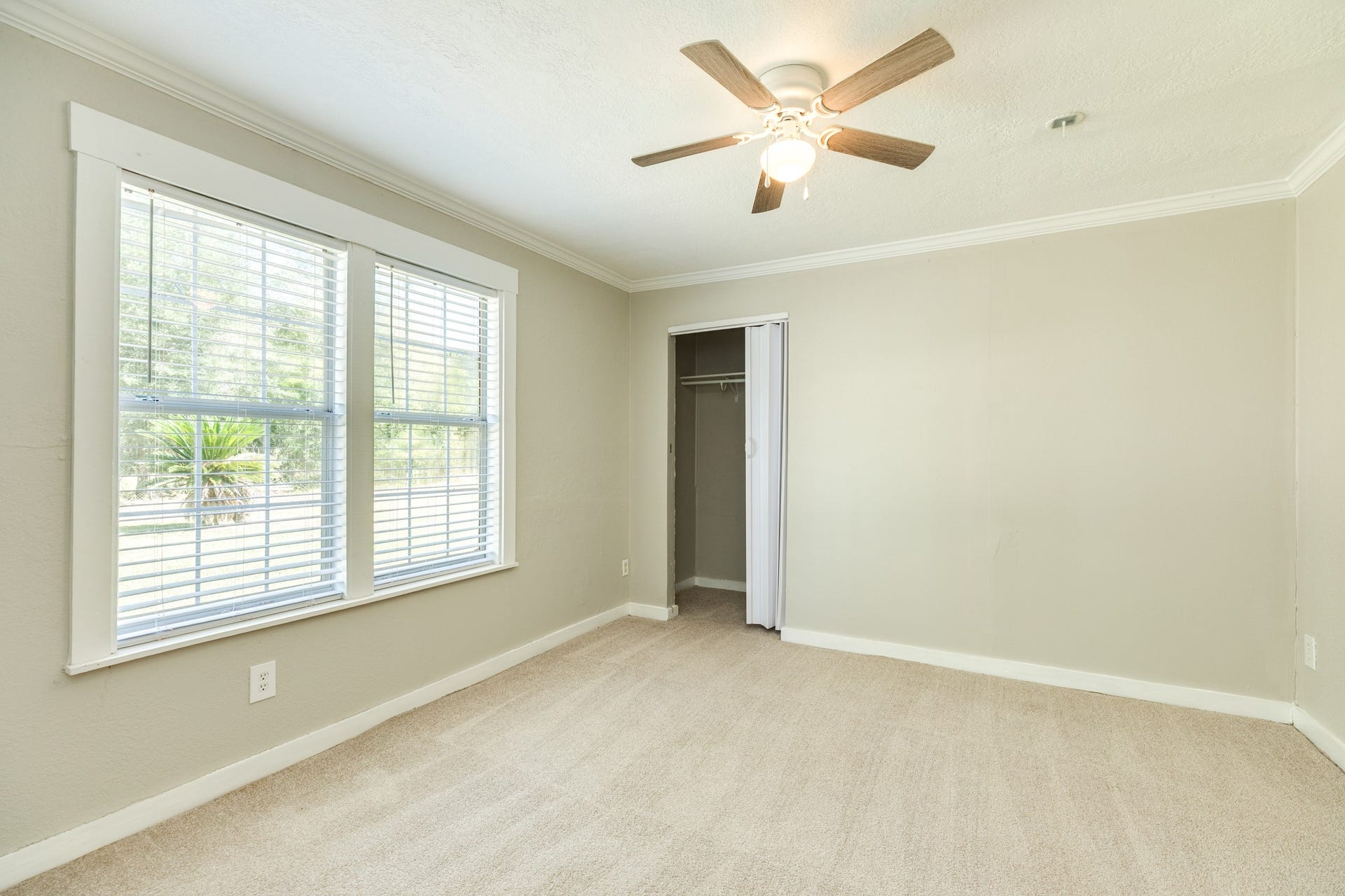 1602 County Road 939, Sweeny, TX 77480 Inviting bedroom features soft neutral carpeting, two large windows with blinds, and a ceiling fan with lighting. A built-in closet with sliding doors provides convenient storage.