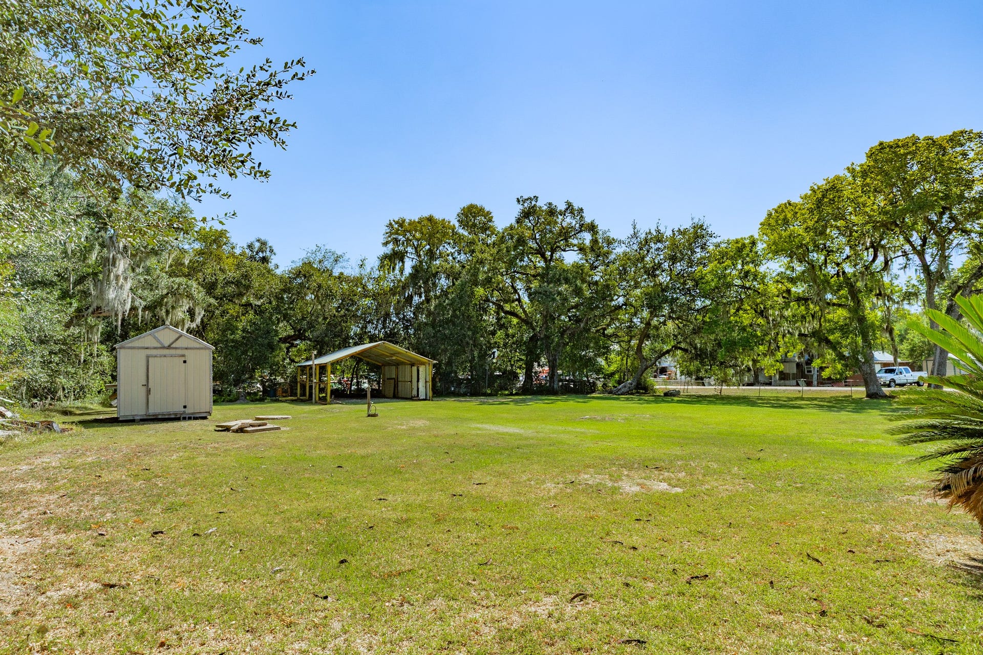 1602 County Road 939, Sweeny, TX 77480 Generous open yard features mature trees, a freestanding storage shed, and a separate covered structure. The expansive grassy setting offers flexibility for outdoor recreation, gardening, and equipment storage.