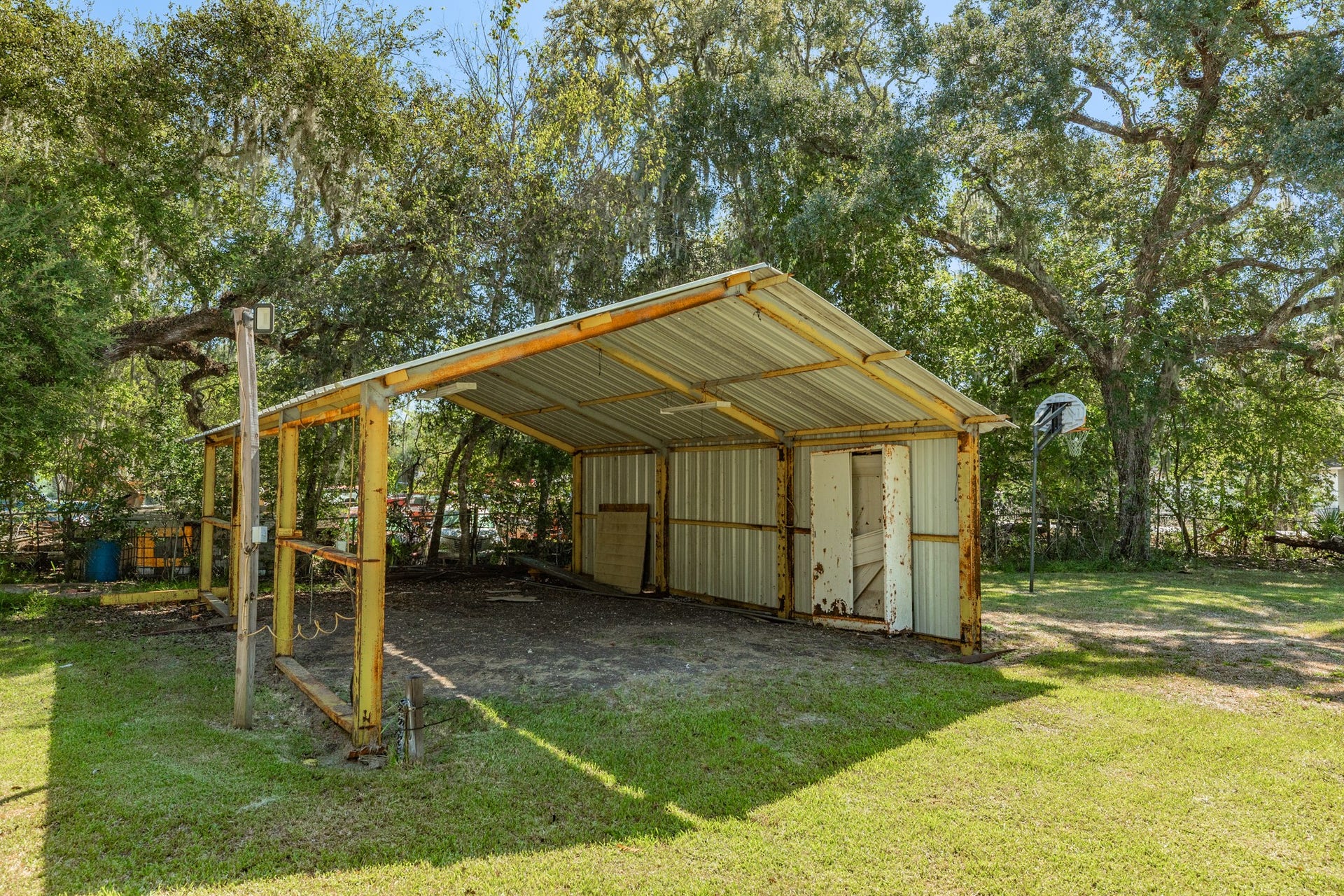 1602 County Road 939, Sweeny, TX 77480 Freestanding metal-roofed structure offers a spacious covered area with open sides, a partially enclosed rear section, and overhead lighting. Ideal for a variety of outdoor storage or workspace needs.