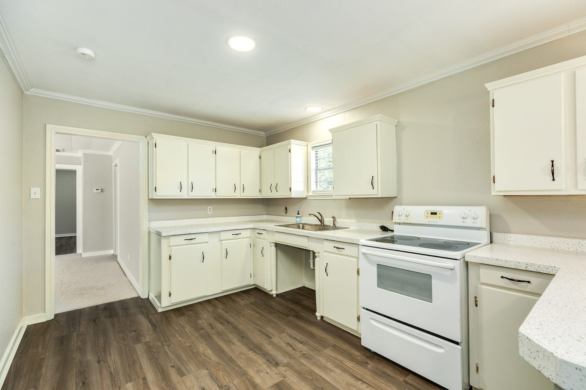 1602 County Road 939, Sweeny, TX 77480 Functional kitchen layout offers abundant white cabinetry, generous counter space, and a white electric range. Recessed lighting, crown molding, and wood-look flooring complete the bright, neutral design.