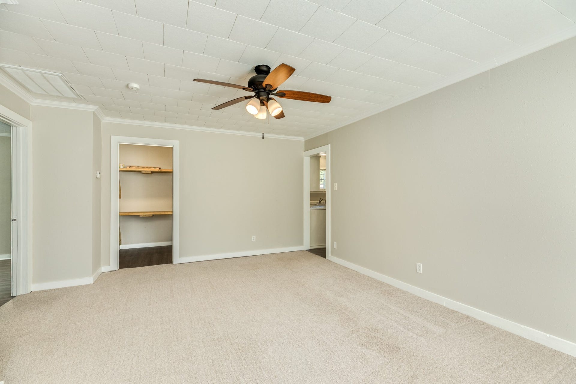 1602 County Road 939, Sweeny, TX 77480 Generously sized living area offers comfortable carpeting, crown molding, and a ceiling fan with warm wood-tone blades. An open doorway provides access to the kitchen, while a recessed shelving area offers convenient storage.