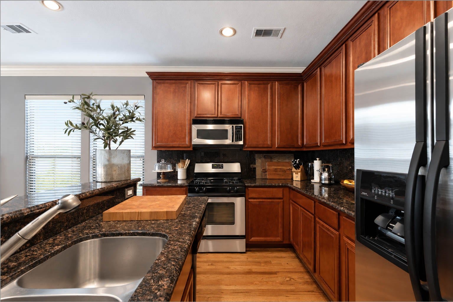 1316 Studer Street, Houston, TX 77007 This closer kitchen view showcases the warmth and craftsmanship of the cabinetry paired with polished granite surfaces and stainless steel appliances. The efficient arrangement provides abundant preparation and storage space.