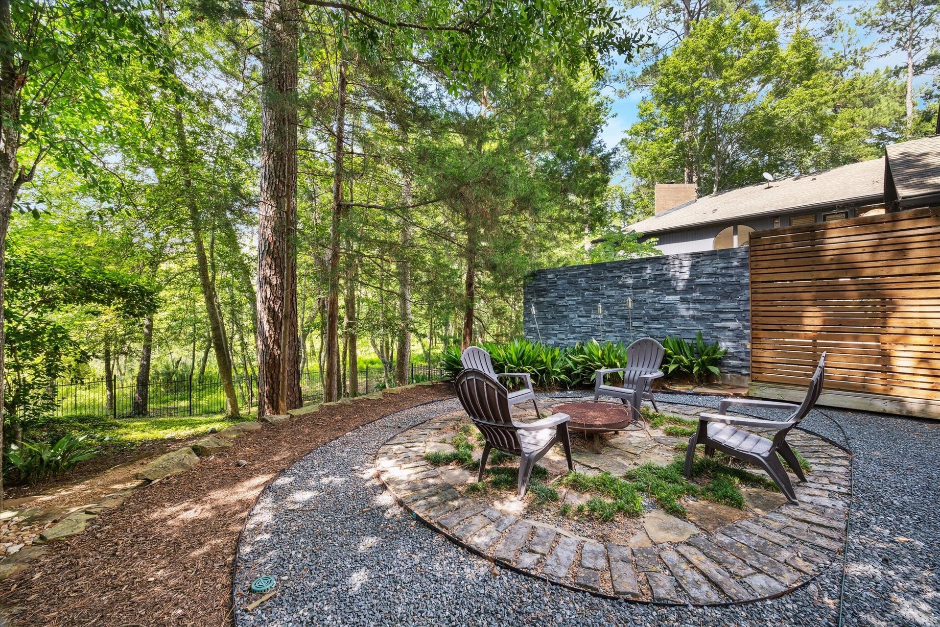 23414 Holly Hollow Street, Tomball, TX 77377 Cozy outdoor fire pit area nestled among mature trees, offering a serene, private retreat perfect for relaxing evenings or entertaining guests in a natural, wooded setting.