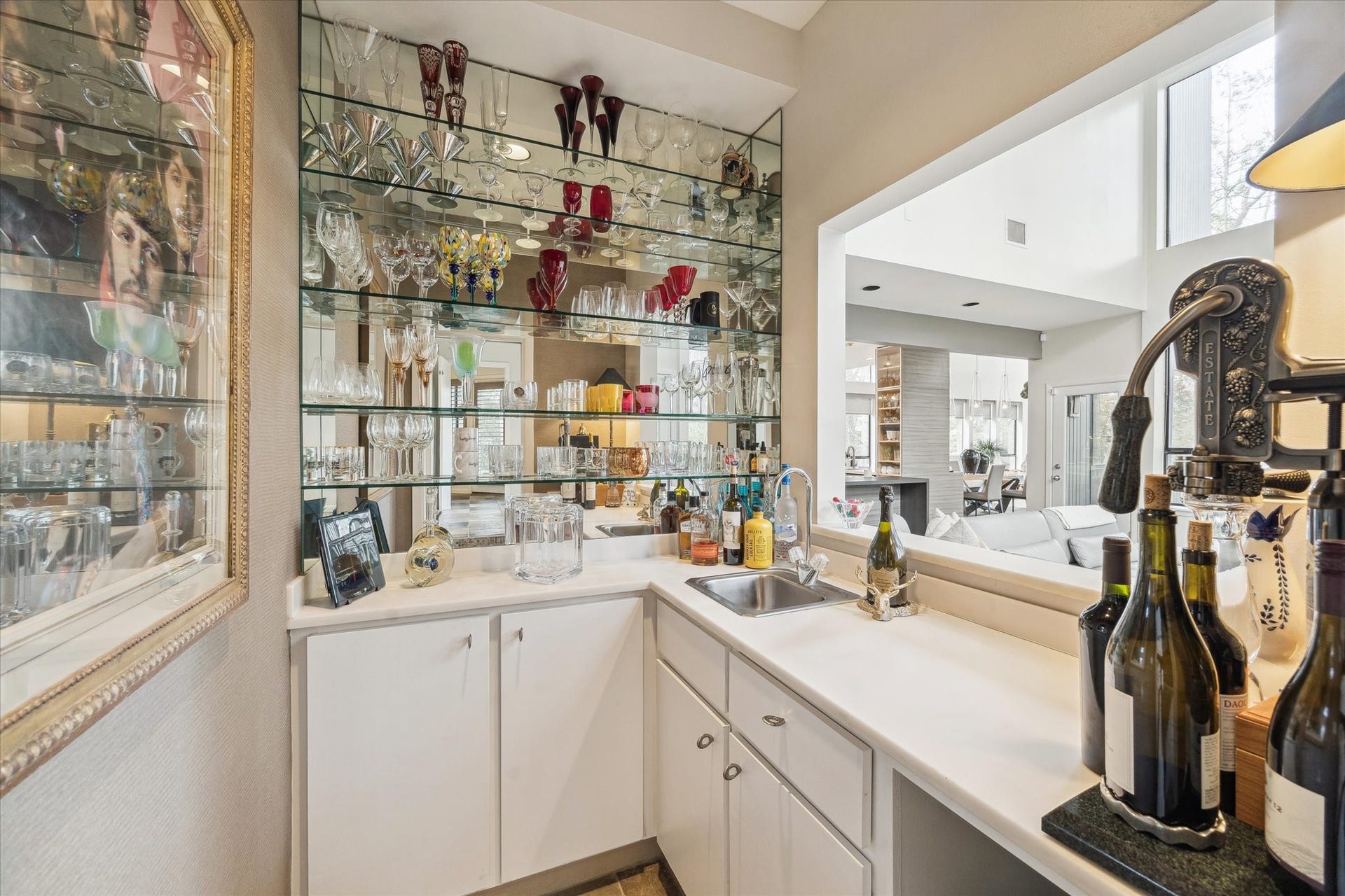 23414 Holly Hollow Street, Tomball, TX 77377 Sophisticated wet bar highlighted by a full mirrored wall and glass shelving, creating a dramatic focal point. Custom lower cabinetry provides generous storage, blending form and function for effortless entertaining and elevated gatherings.
