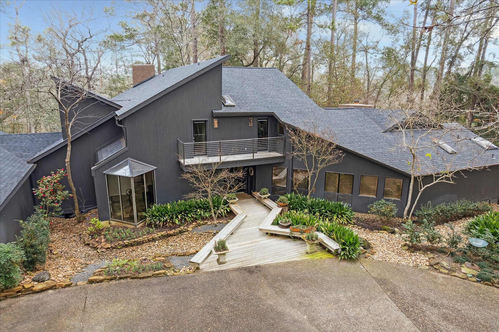 23414 Holly Hollow Street, Tomball, TX 77377 The exterior features clean architectural lines, a modern gabled roof, and a sophisticated neutral faade that blends seamlessly with the natural surroundings.