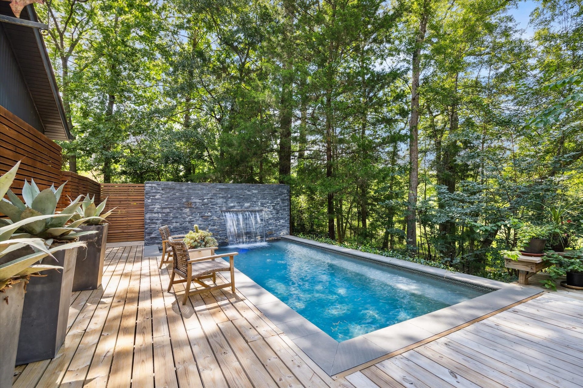 23414 Holly Hollow Street, Tomball, TX 77377 The swimming pool with a stone wall water feature and a sprawling wooden deck invites you and your guests to relax under the sun or moonlight.