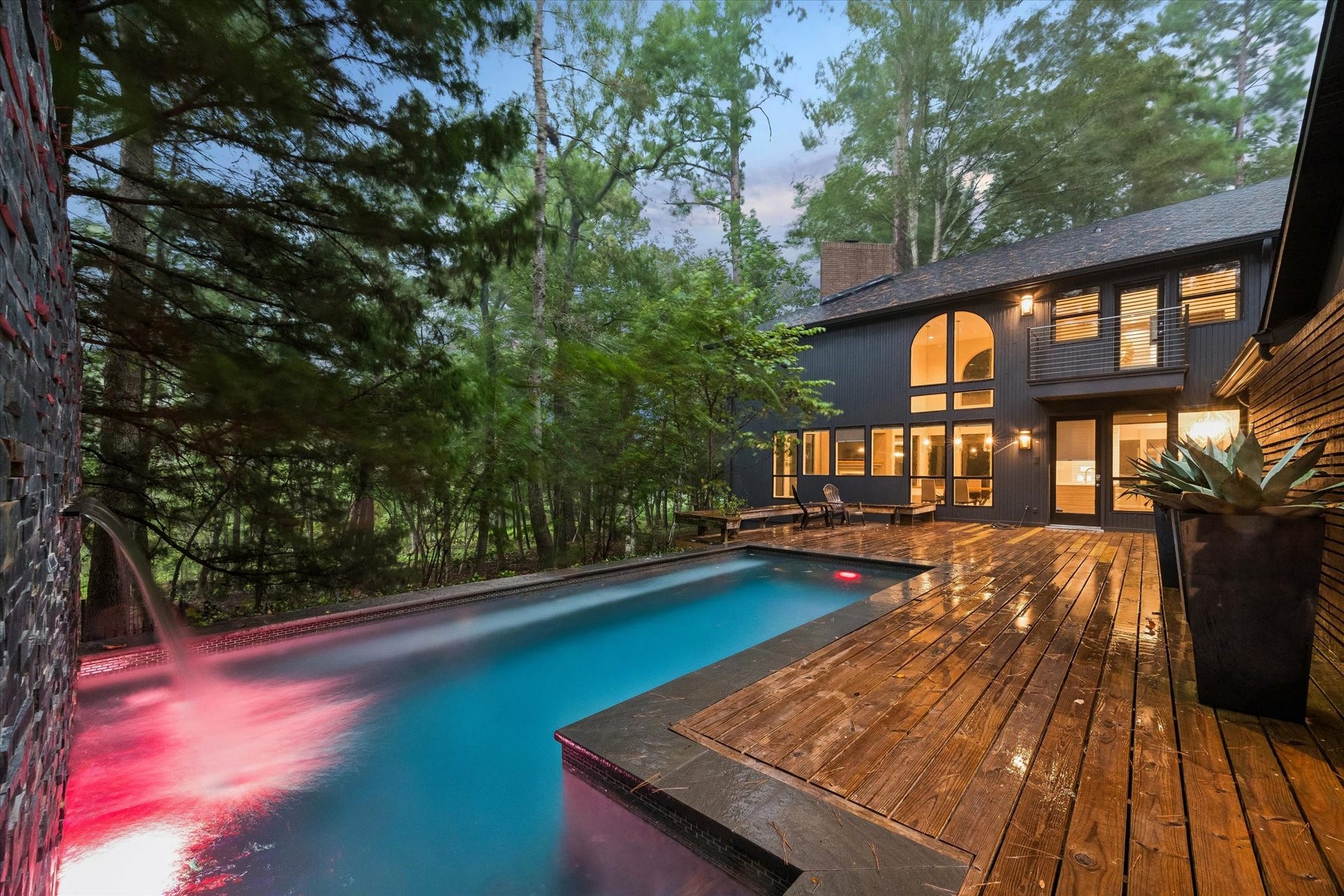 23414 Holly Hollow Street, Tomball, TX 77377 A raised water feature cascades into the pool below, adding both sound and sparkle to this wooded backyard retreat. The expansive wood deck wraps the pool's edge, offering plenty of room to lounge while taking in the home's striking vertical-plank architecture.