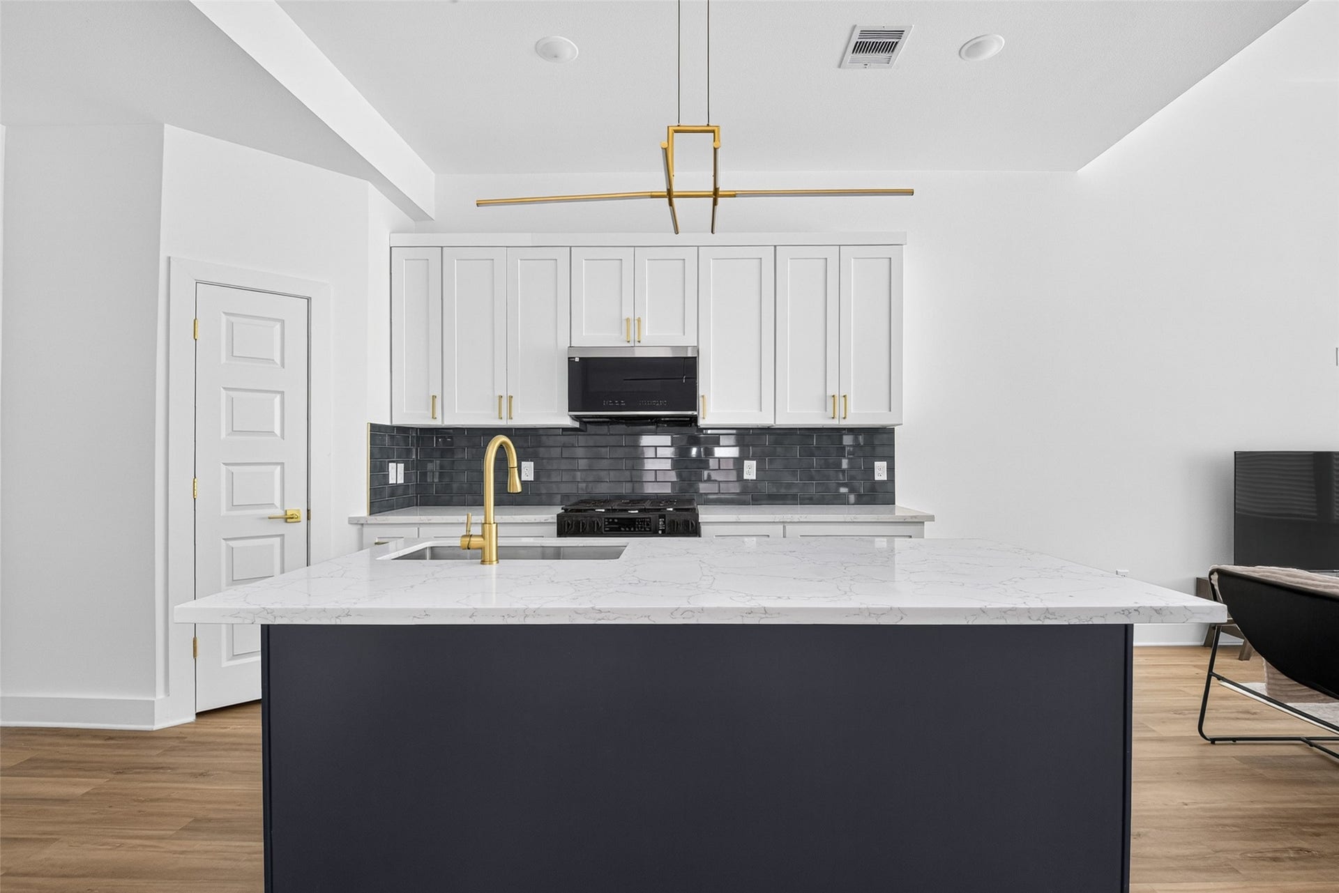 9309 Caddo Road, #A, Houston, TX 77078 Modern luxury at its finest. High-end white shaker cabinets frame a rich navy blue island topped with white marble-patterned quartz, perfectly finished with elevated gold hardware for a high-design feel.