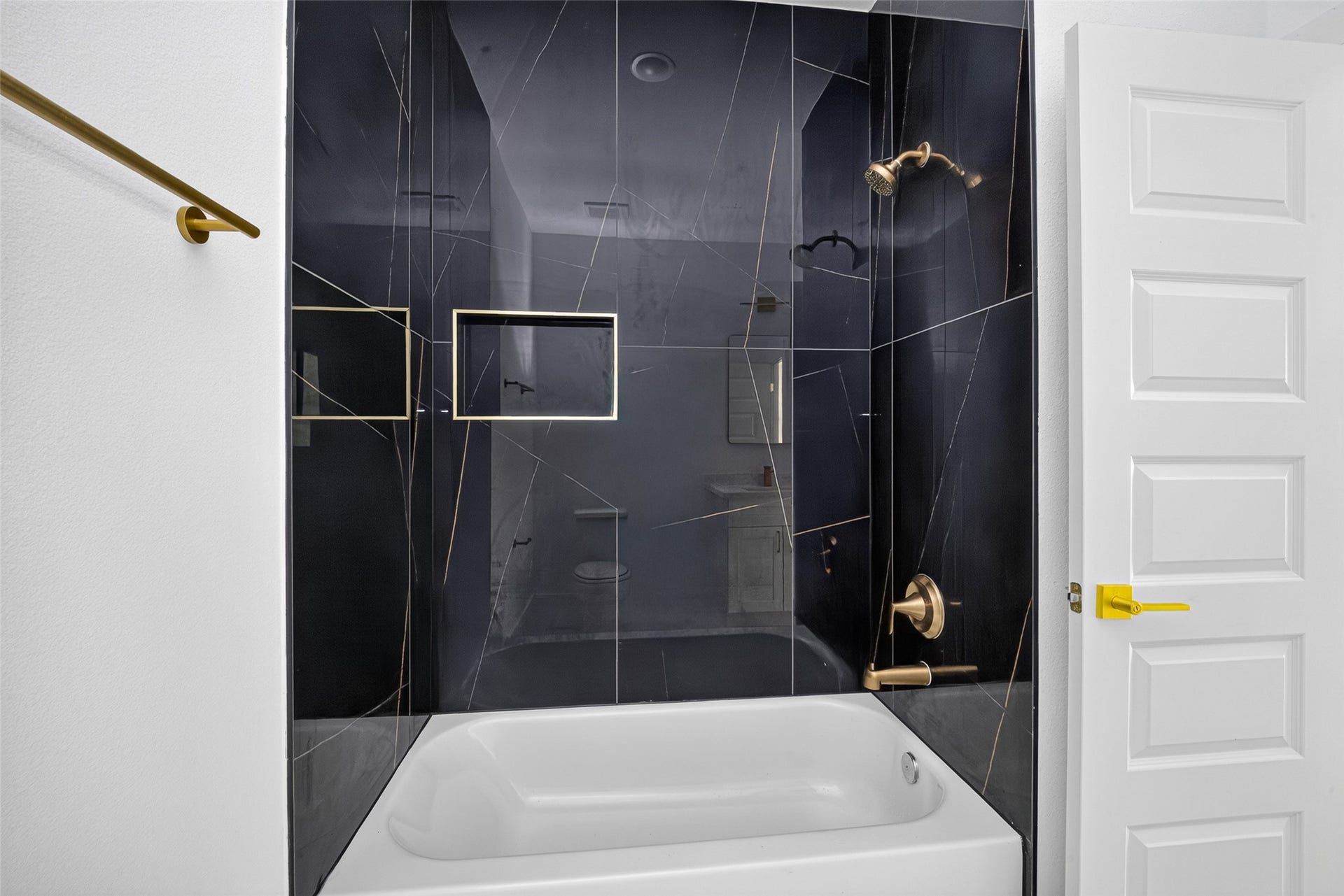 9309 Caddo Road, #A, Houston, TX 77078 Dramatic dark marble-patterned tile surrounds a deep soaking tub and sleek glass shower, delivering pure everyday luxury.