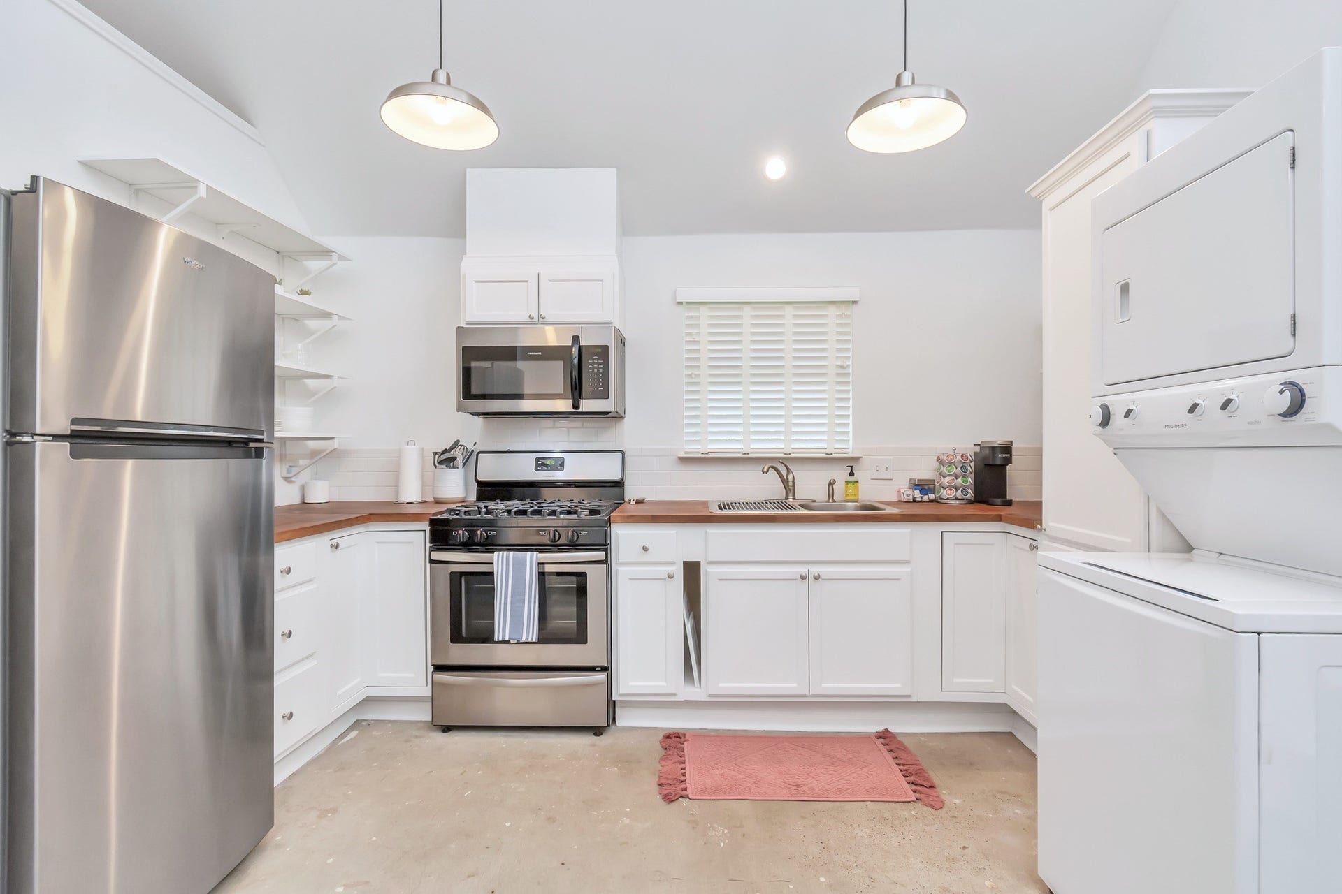 A spacious and thoughtfully designed kitchen featuring stainless steel appliances, walnut butcher block countertops, and timeless subway tile backsplash.