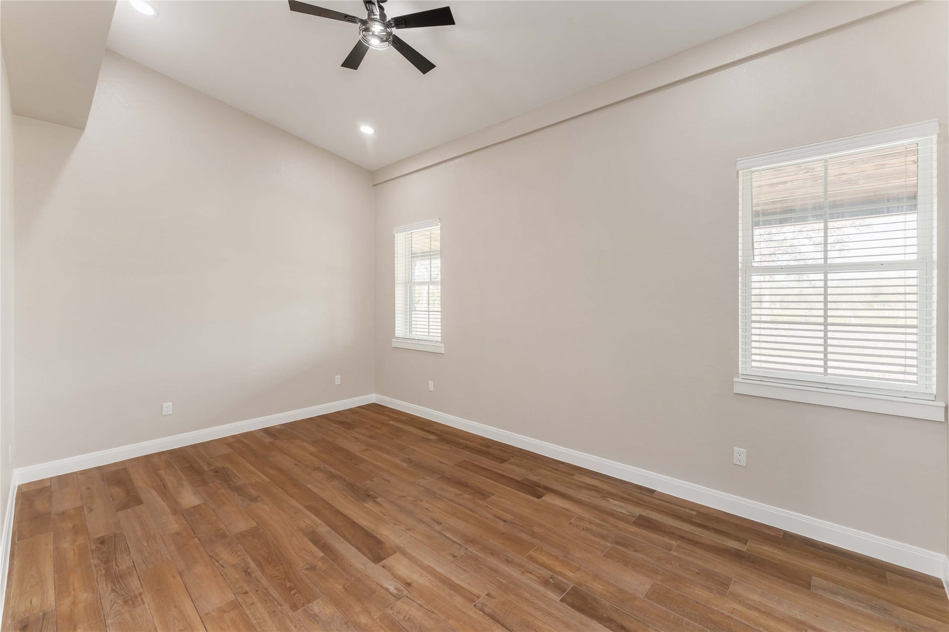 4864 County Road 182 Off, Alvin, TX 77511 This room features a high ceiling with a modern ceiling fan, warm wood flooring, and neutral walls. It has large windows that allow natural light to fill the space, creating a bright and inviting atmosphere.