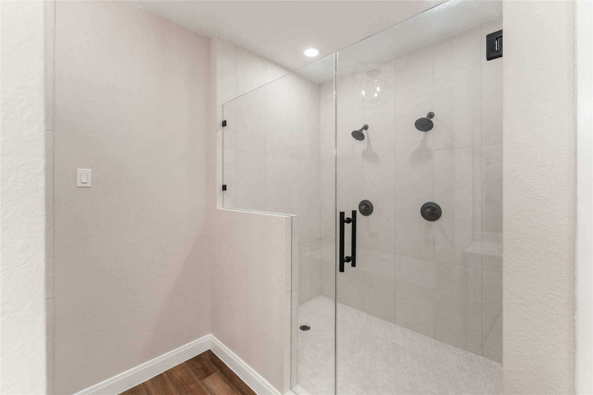 4864 County Road 182 Off, Alvin, TX 77511 This photo showcases a modern, spacious shower with a glass door, dual showerheads, and sleek black fixtures. The neutral tile design and recessed lighting create a bright and elegant atmosphere.