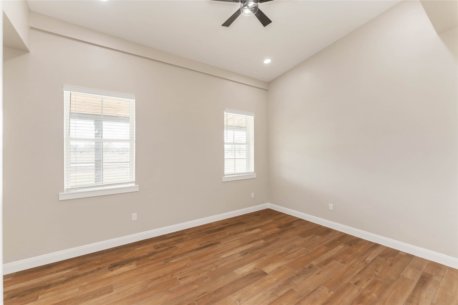 4864 County Road 182 Off, Alvin, TX 77511 This room features a spacious layout with high ceilings, tile wood-style flooring, taupe walls, and ample natural light from two large windows. A ceiling fan adds comfort to the space. Perfect for a bedroom or home office.