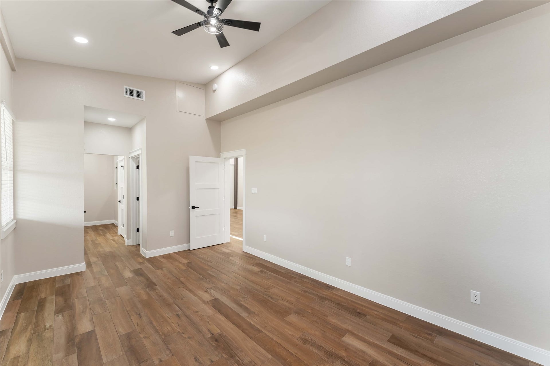 4864 County Road 182 Off, Alvin, TX 77511 Bright and spacious room with high ceilings, tile wood-style flooring, and recessed lighting. Features a ceiling fan and multiple doors leading to other areas, offering a modern and open feel.