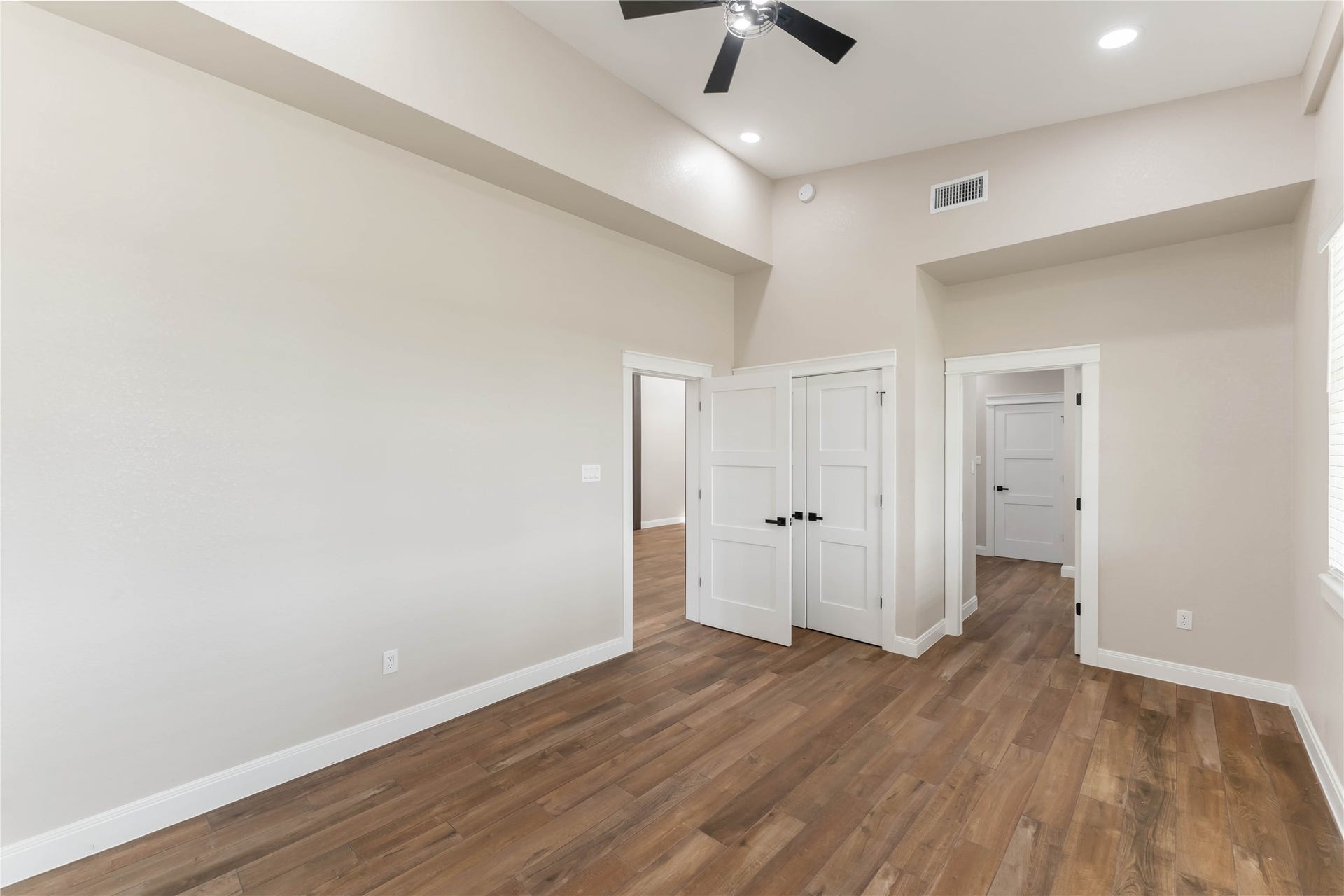 4864 County Road 182 Off, Alvin, TX 77511 This spacious interior features high ceilings, tile wood-style flooring, and taupe walls. It includes a ceiling fan and recessed lighting, providing a modern and airy feel. Multiple doors lead to adjacent rooms, enhancing connectivity throughout the space.