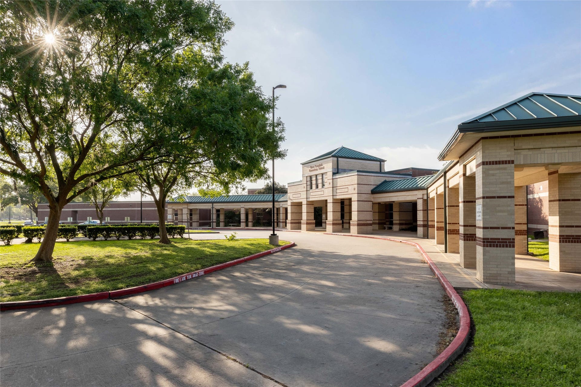 Beautiful community entrance surrounded by mature trees and manicured landscaping.