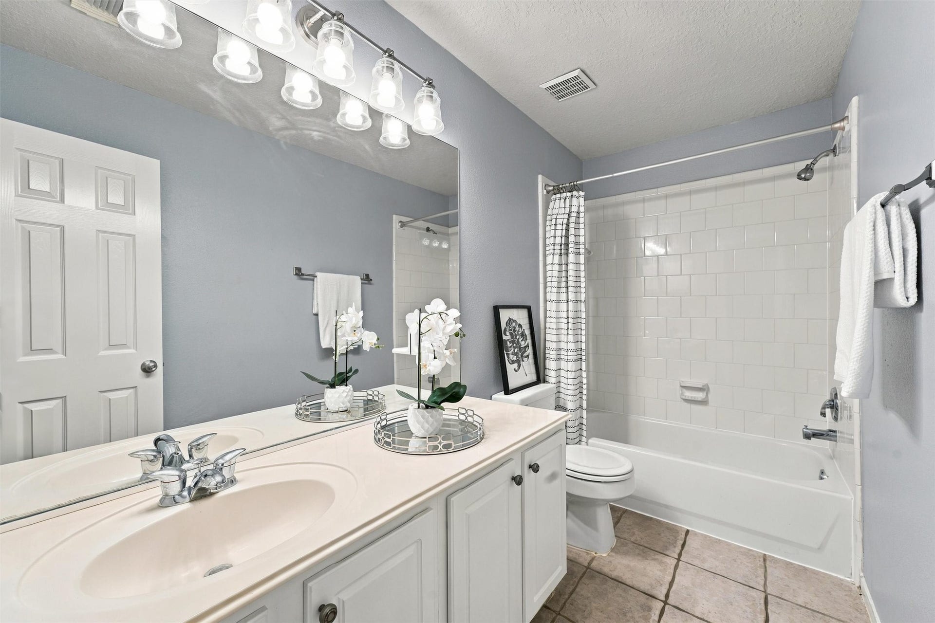 Upstairs bathroom featuring dual sinks, a spacious vanity, and a shower and tub combination.