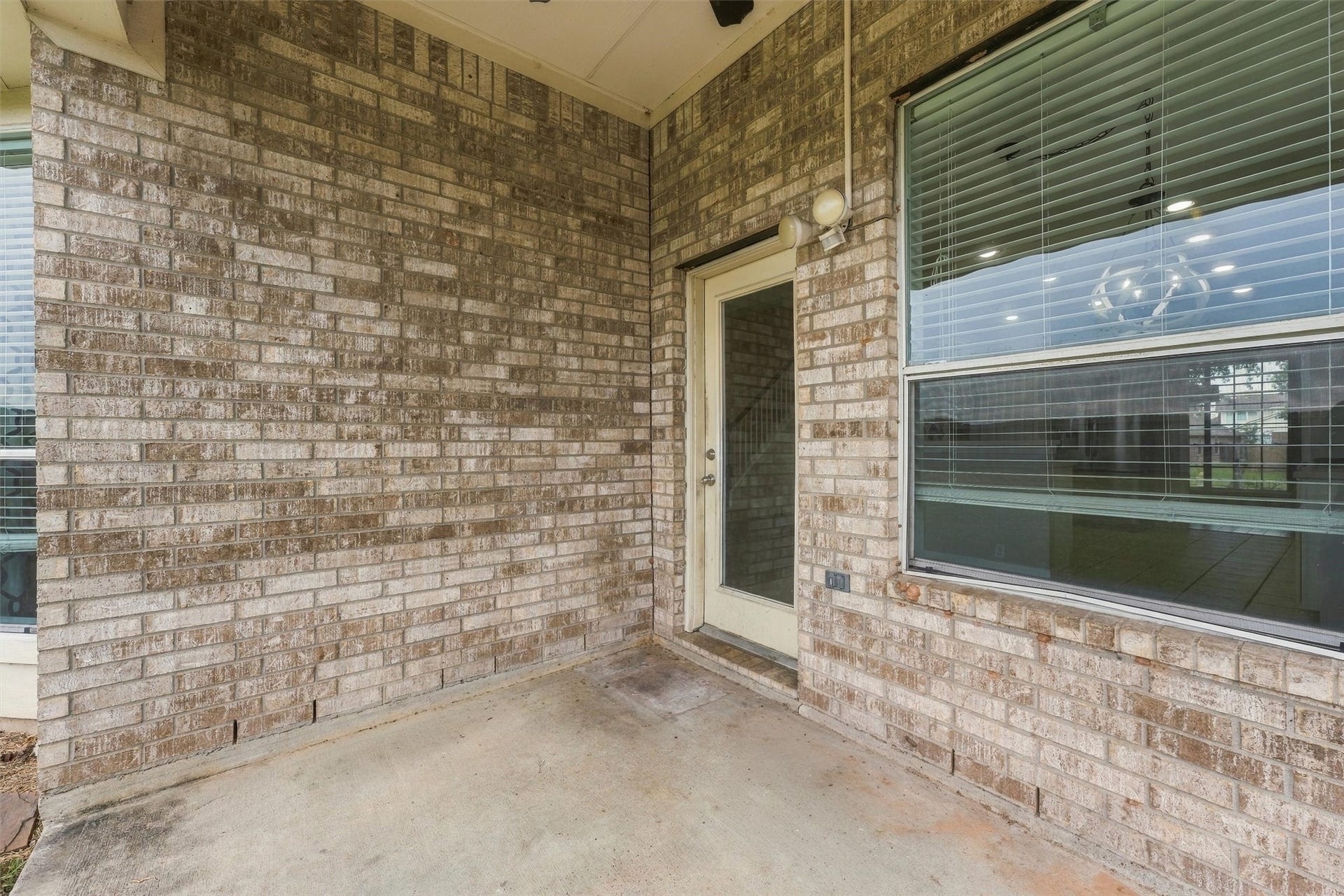 Another view of the covered patio featuring a brick exterior and backyard access.