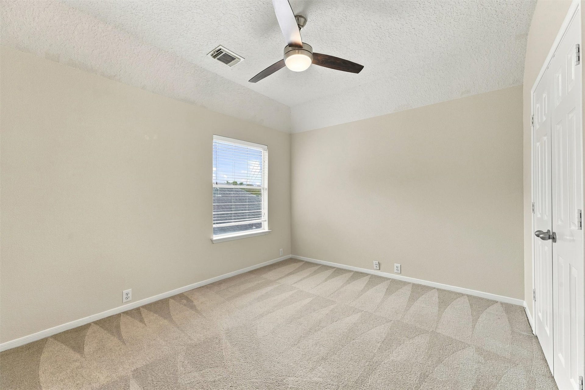 Another secondary bedroom offering natural light, neutral flooring, and flexible living space.