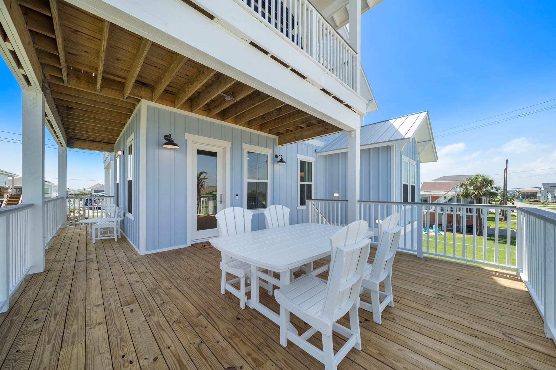 Spacious wooden deck perfect for outdoor dining, featuring a charming table set and coastal views.