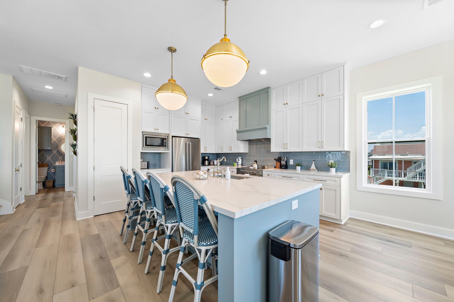 Bright and spacious kitchen featuring a large island with seating, elegant pendant lighting, and sleek stainless steel appliances, all complemented by a stylish backsplash and ample cabinetry.