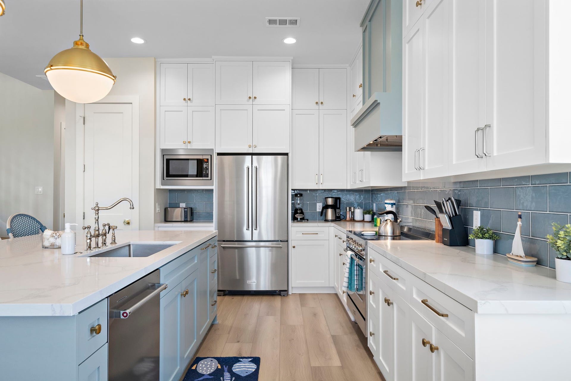 Bright and modern kitchen featuring sleek white cabinetry, stainless steel appliances, and a stylish blue tile backsplash.