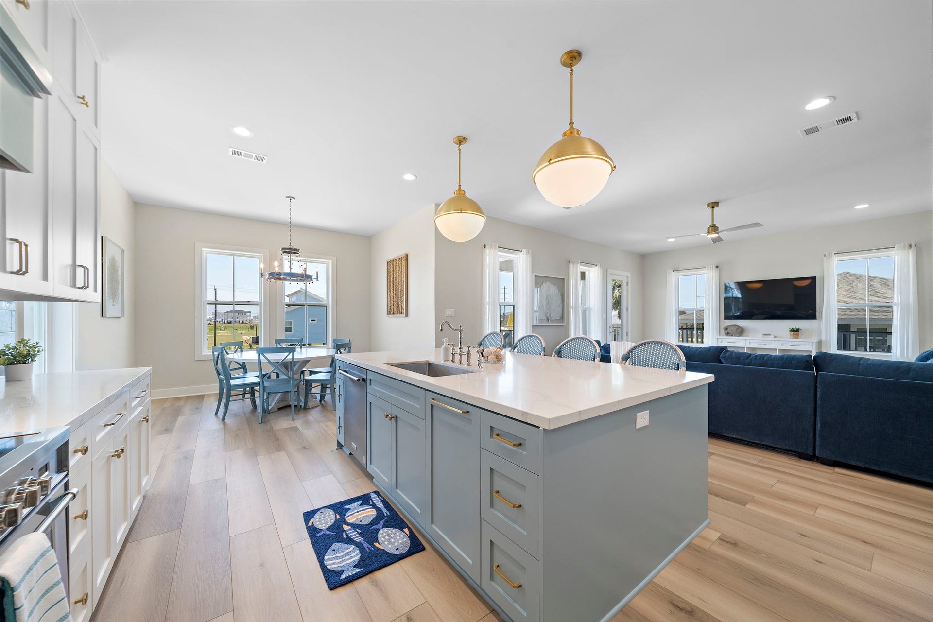 Spacious and bright open-concept living area featuring a modern kitchen with a large island, elegant pendant lighting, and sleek cabinetry, seamlessly flowing into a cozy dining and living space.