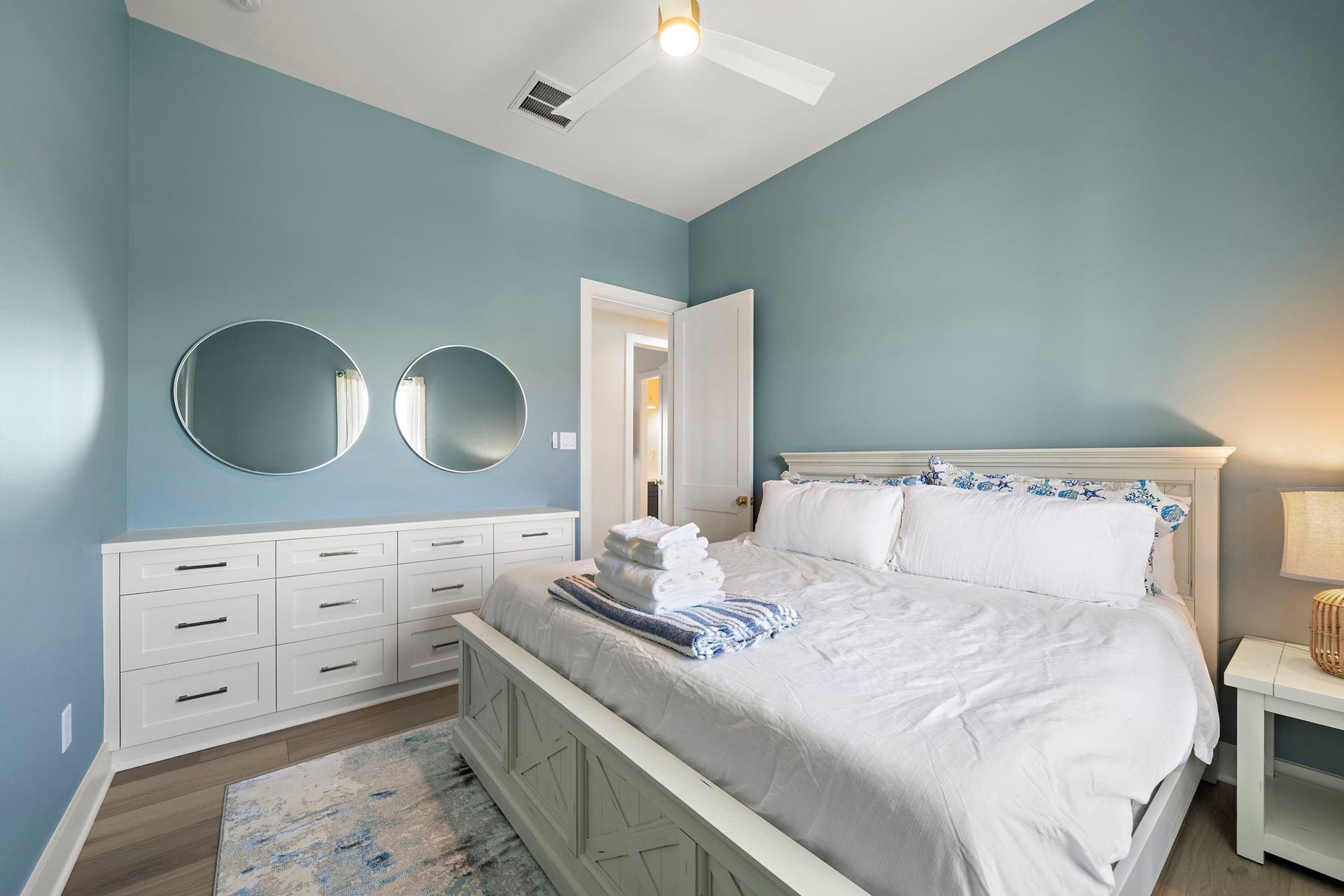 Charming bedroom with soothing blue walls, elegant white furniture, and modern decor, creating a serene and inviting atmosphere.
