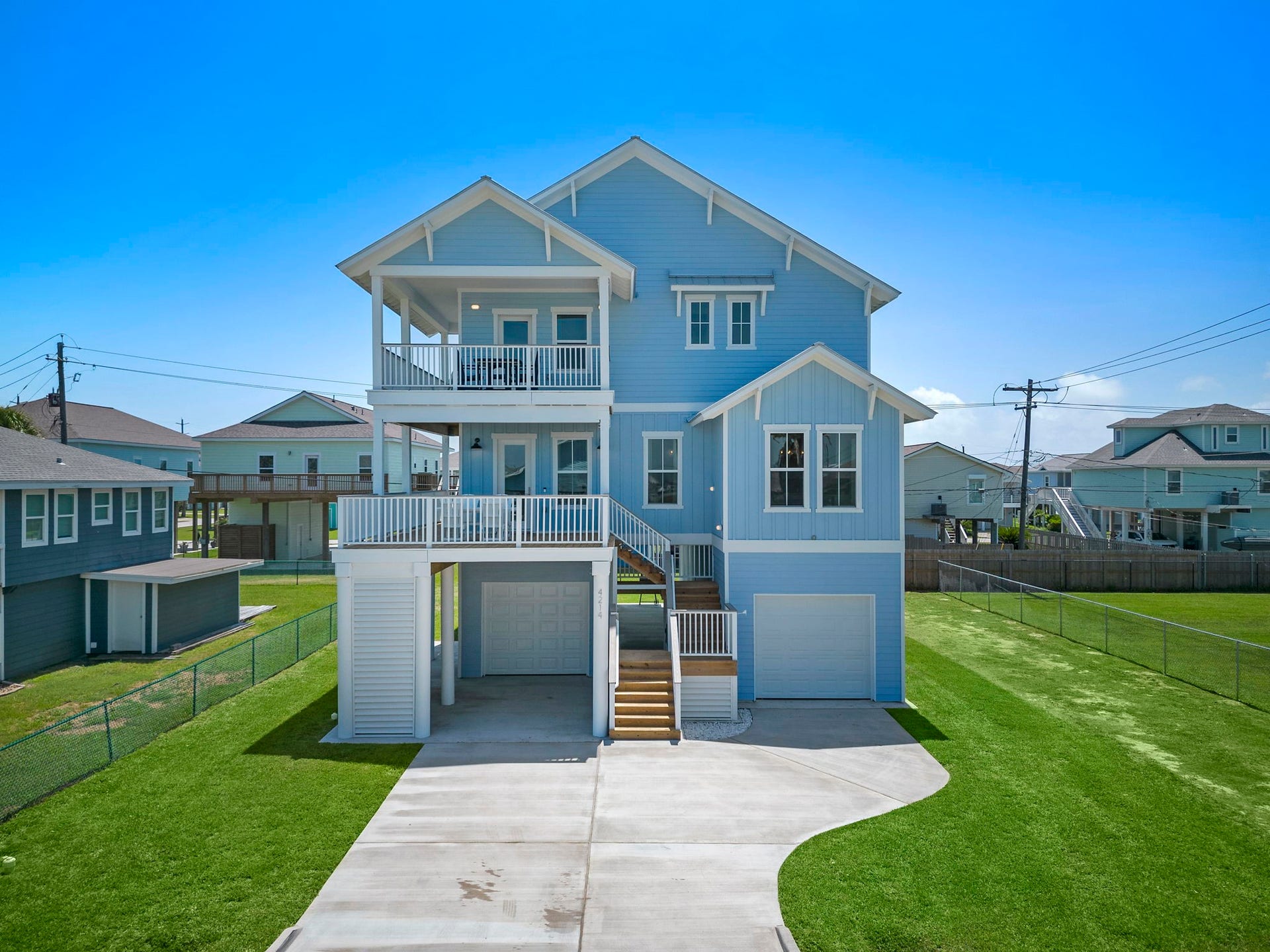Charming coastal home with a fresh blue exterior, spacious balconies, and elevated design offering stunning views. Enjoy a generous driveway and neatly landscaped yard, perfect for coastal living.