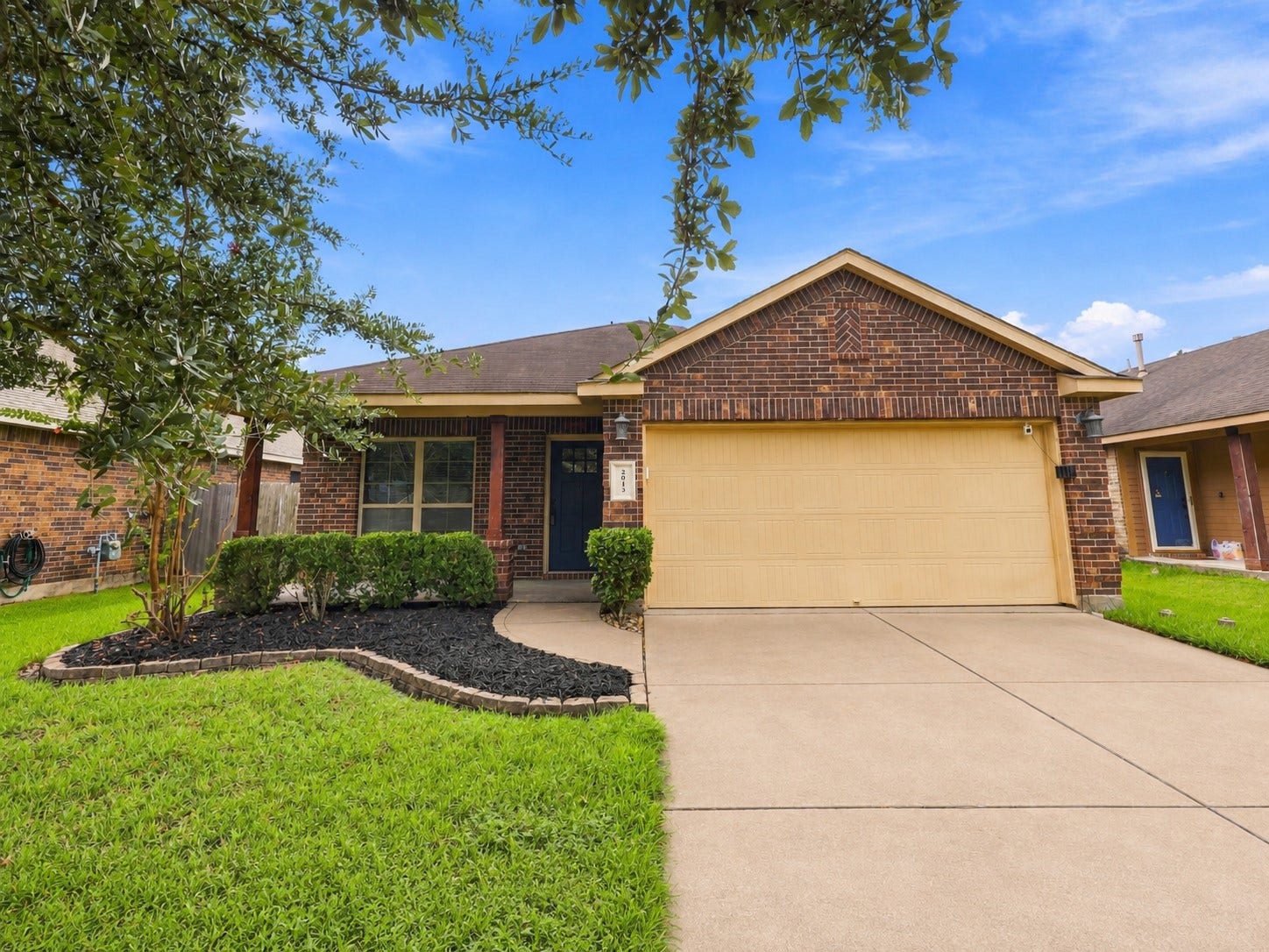 Front exterior with attractive brick elevation, landscaped yard, and attached 2-car garage.