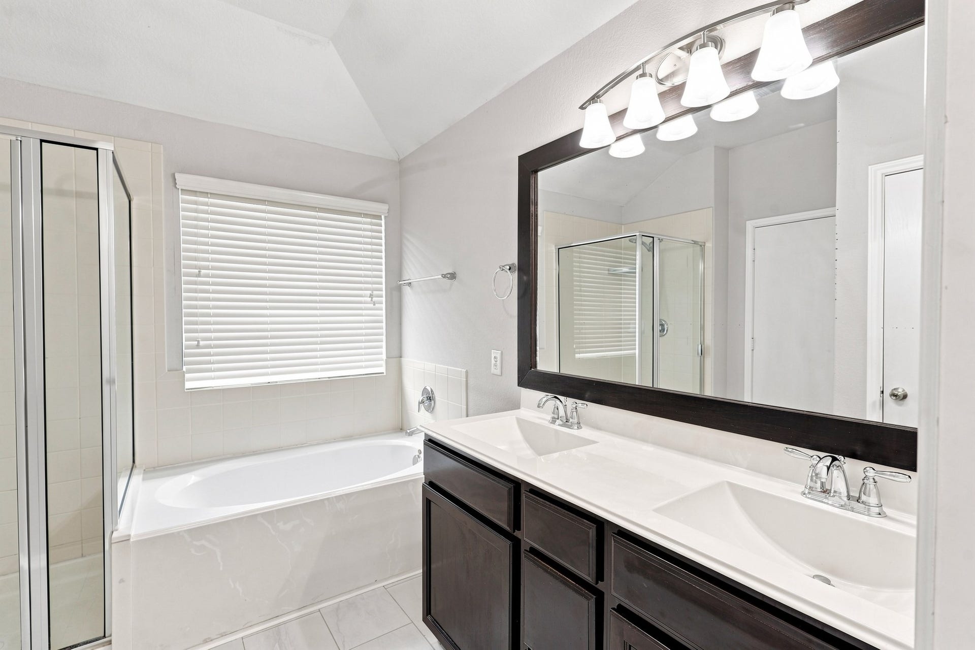 Primary bathroom with dual sinks, large vanity, soaking tub, separate shower, and oversized mirror.