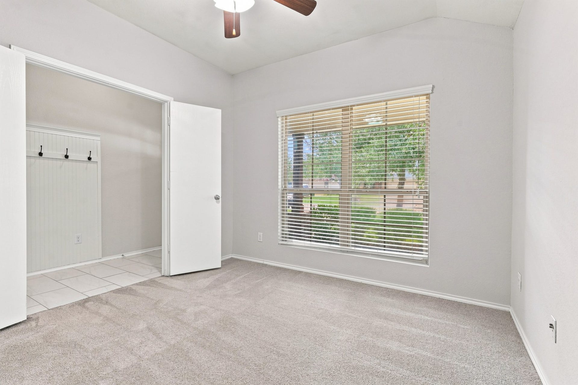 Study/home office with large front-facing window and convenient access to the entry, featuring a built-in coat rack with hooks.