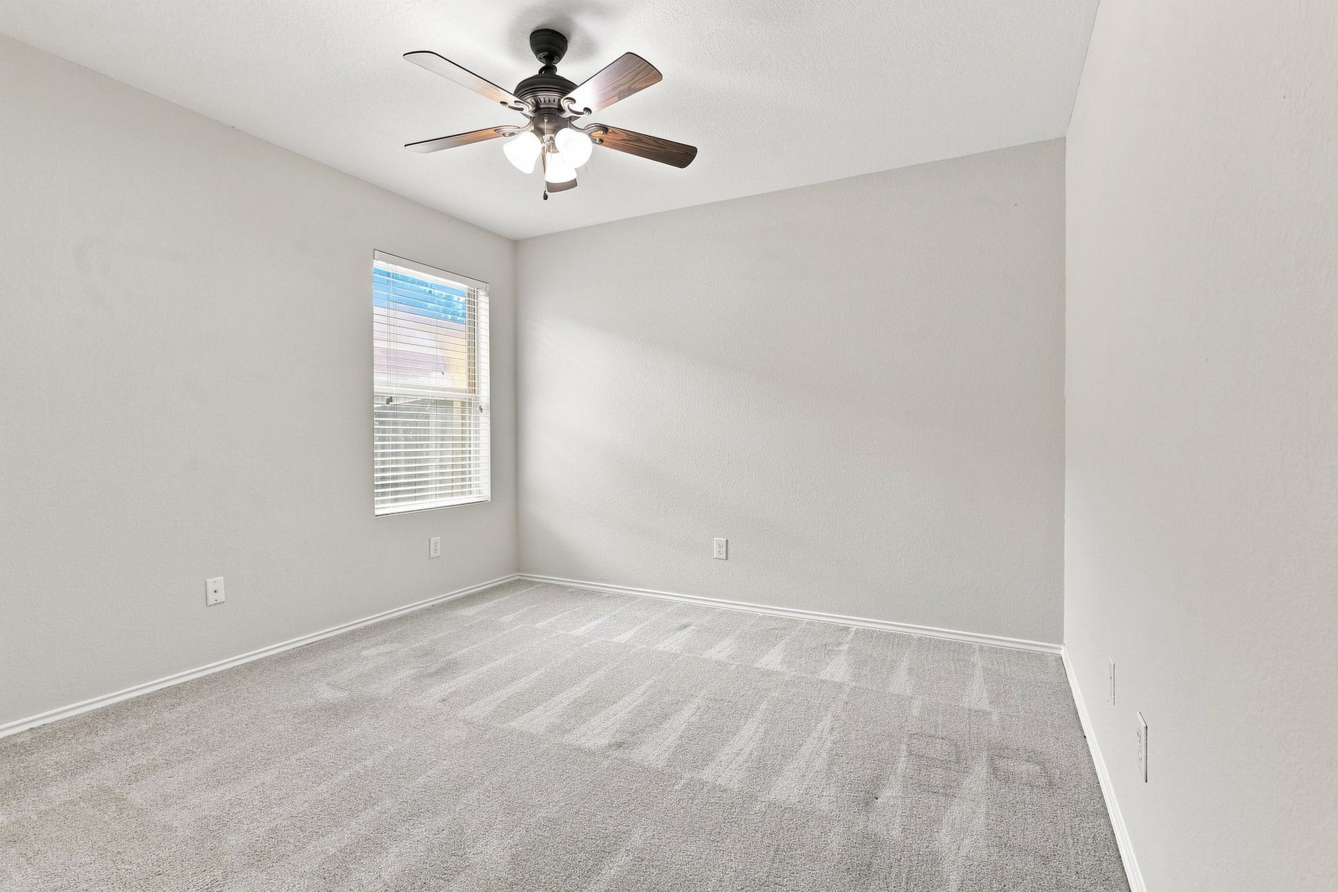 Third bedroom with neutral carpet, ceiling fan, and natural light.
