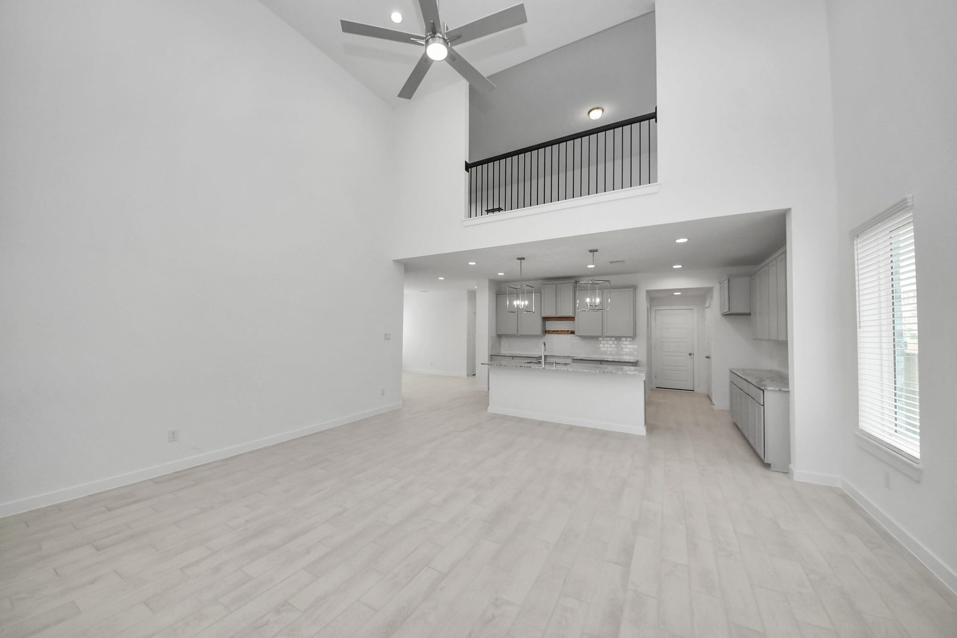 Relax and unwind in this inviting family room, illuminated by abundant natural light streaming in through tall windows, complemented by high ceilings and stunning flooring. Stay comfortable year-round with the gentle breeze from the ceiling fan, creating the perfect atmosphere for family gatherings.