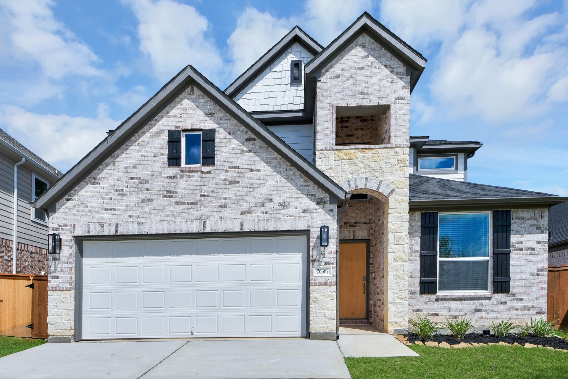 This home boasts lush green grass and meticulous landscaping. Its premium elevation showcases an exquisite blend of brick and stone features, complemented by modern coach lighting