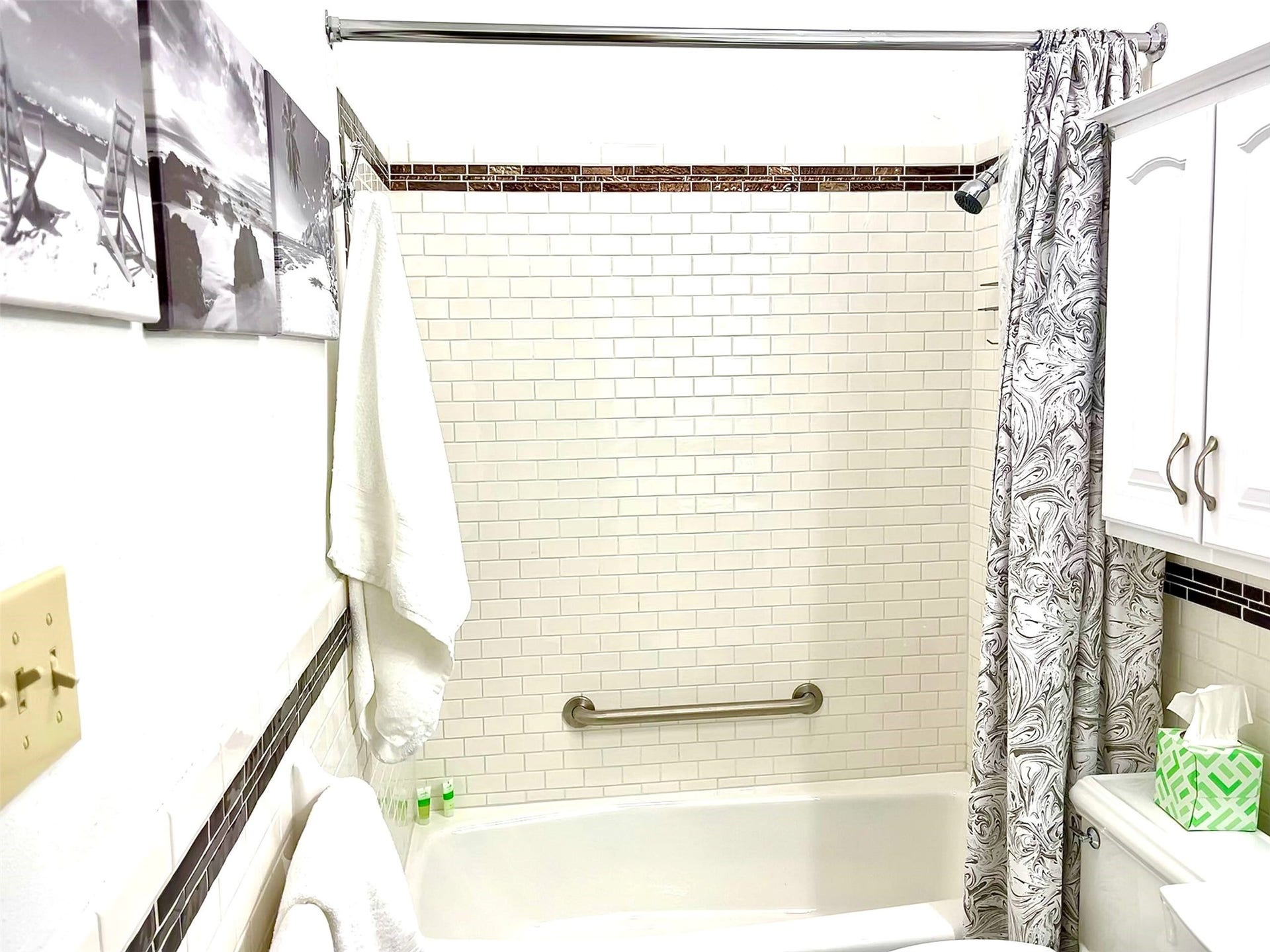 Bright and inviting bathroom featuring classic white subway tiles, a modern shower curtain, and ample storage with a sleek cabinet.