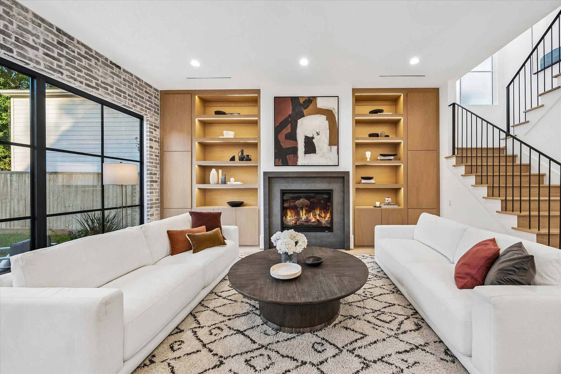 [Familly Room] Gas fireplace with stone surround. Custom built-ins with lighted display shelving and concealed storage.