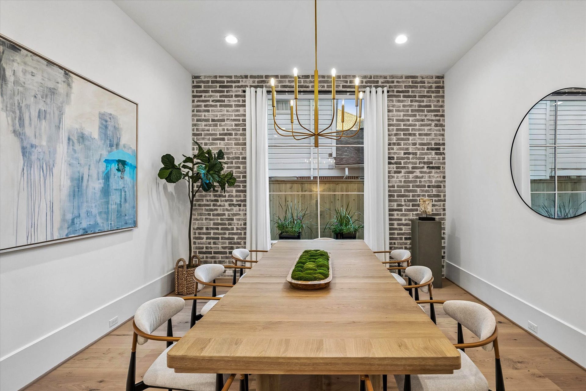 [Formal Dining] The formal dining room features a brick accent wall and is adjacent to the wet bar. This space was designed for effortless entertaining. Visual Comfort brass chandelier.