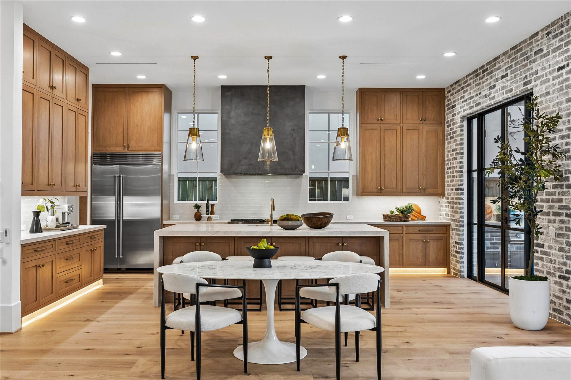 4230 Riley Street, Houston, TX 77005 Chefs kitchen with warm oak cabinetry, a plaster range hood, and a waterfall island with Visual Comfort pendants.