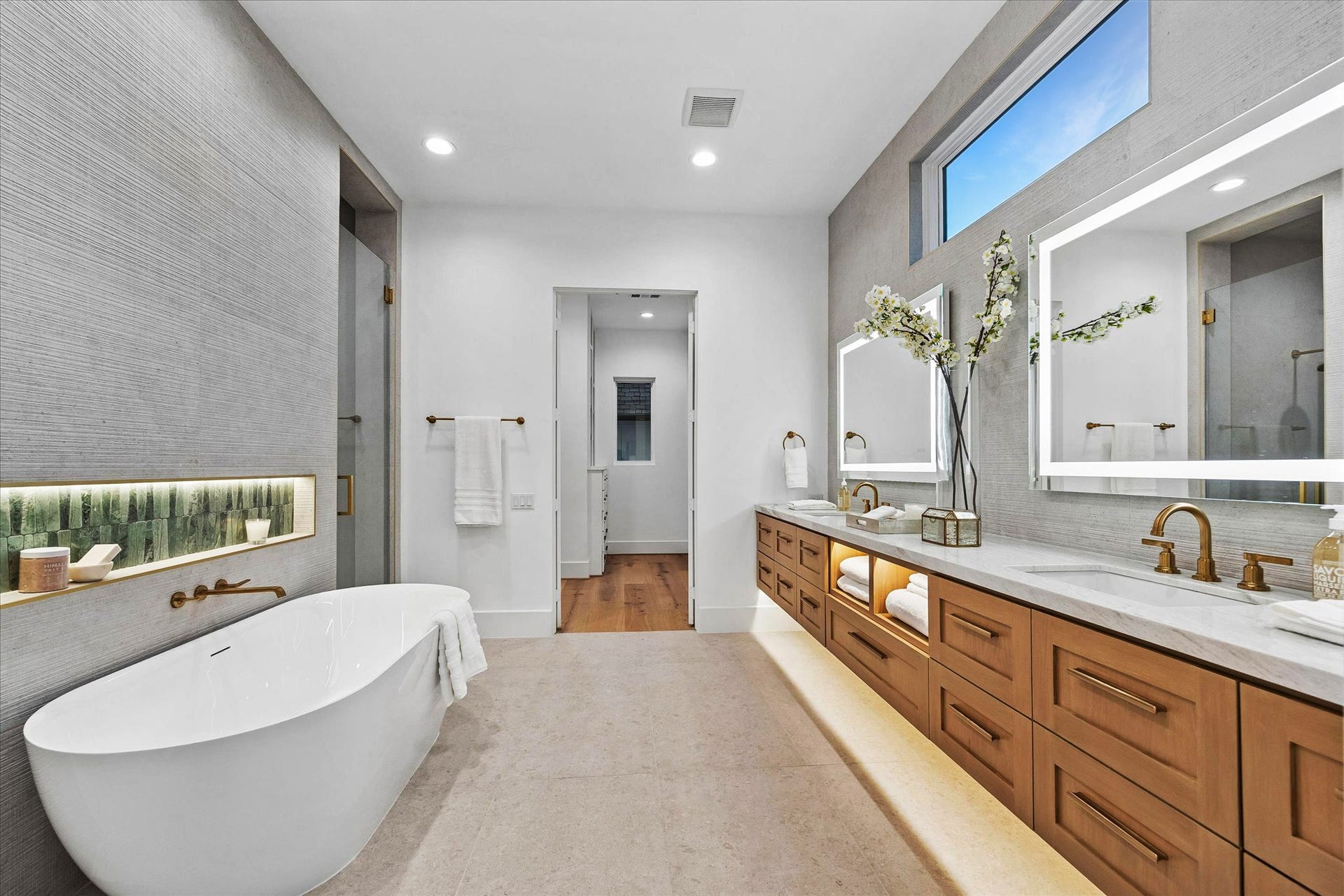 [Primary Bathroom] Spacious quartzite primary spa-like bath with soaking tub, floating vanities, dual sinks, and  shower with built-in seating.