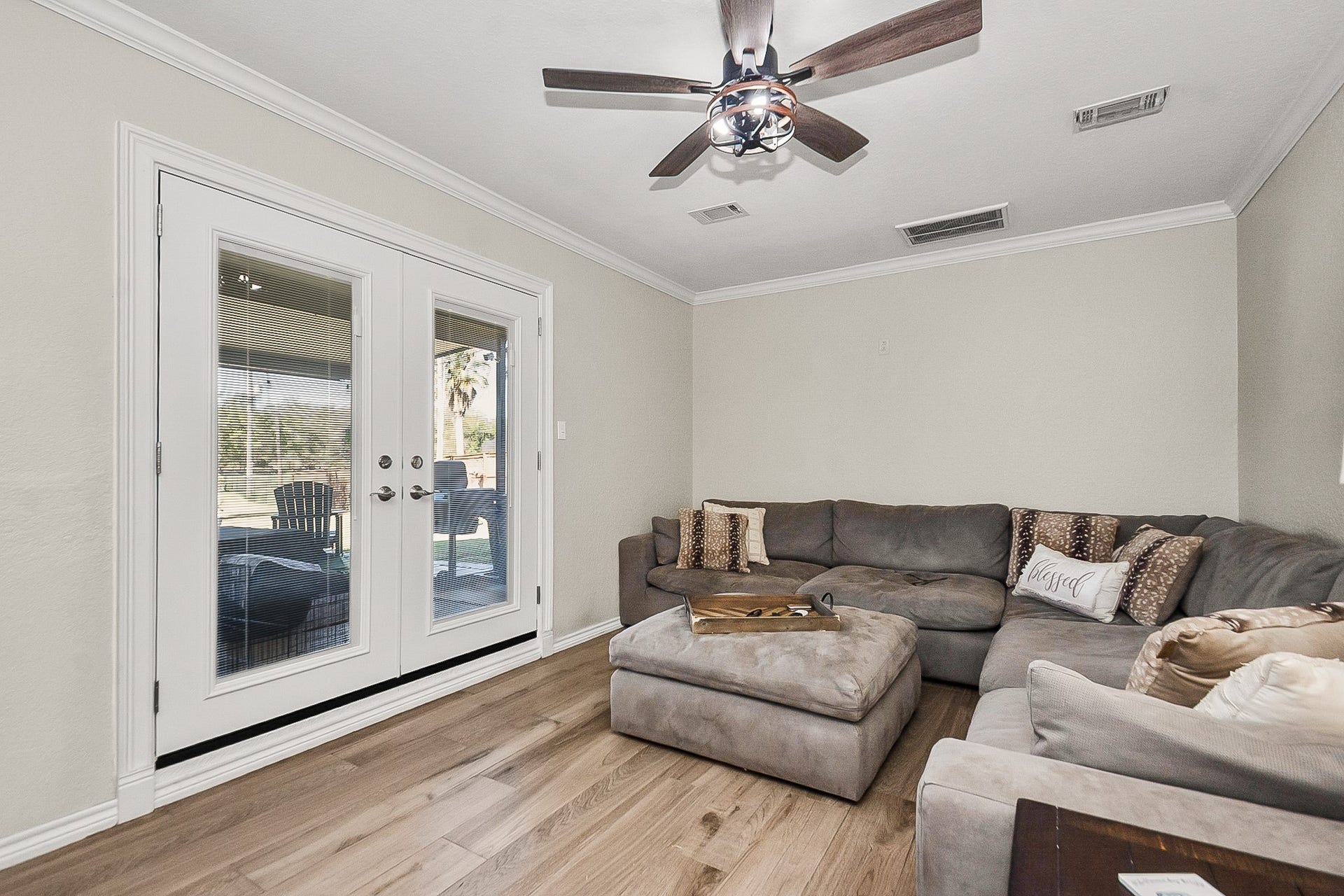 928 Oleander Street, Lake Jackson, TX 77566 Cozy living room fits a plush size sectional sofa with stylish ceiling fan, offering a bright and inviting space with glass doors leading to an outdoor patio.